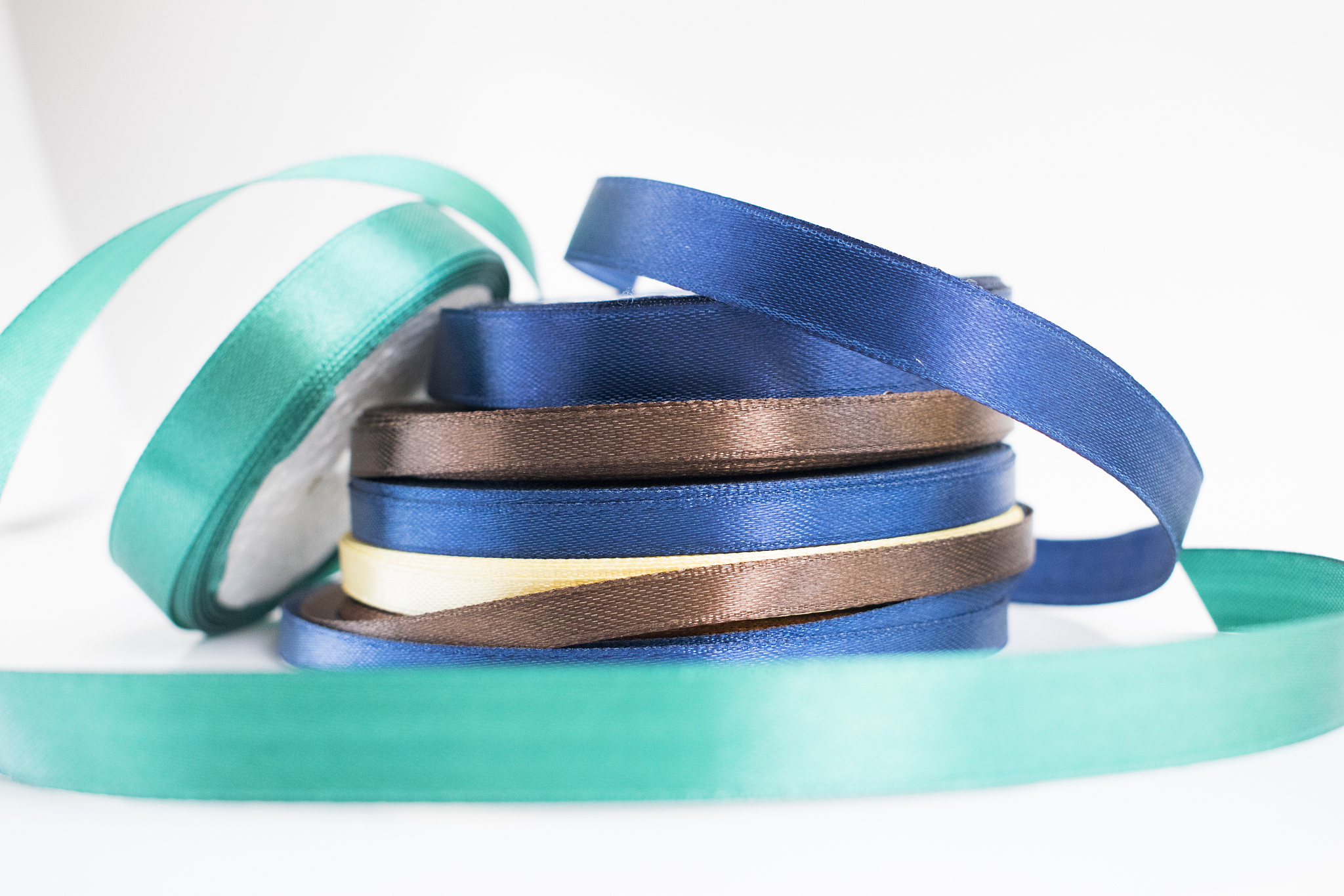 stack of satin ribbon coils. blue, green, brown and yellow ribbo