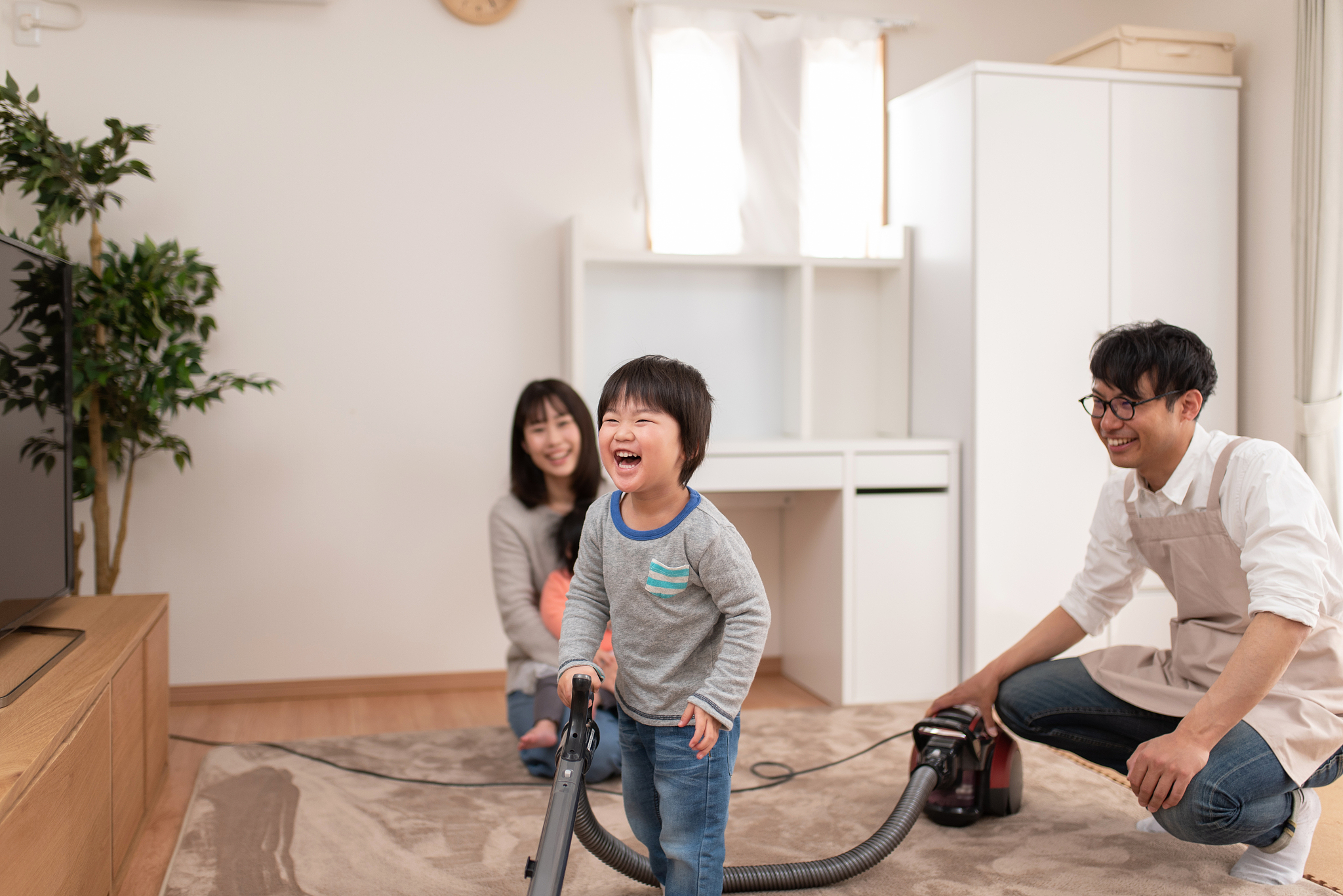 child vacuuming in living room with father