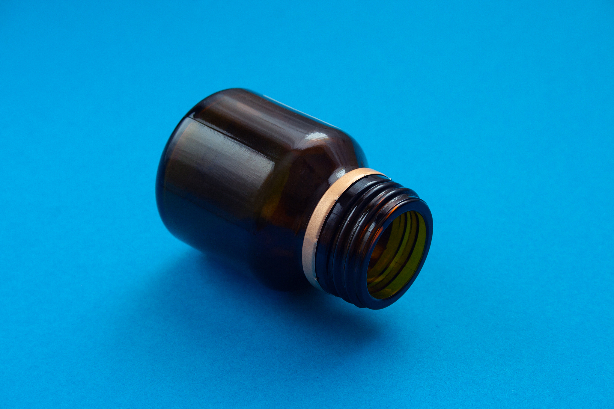 empty glass dark bottle without pills on blue background. medici