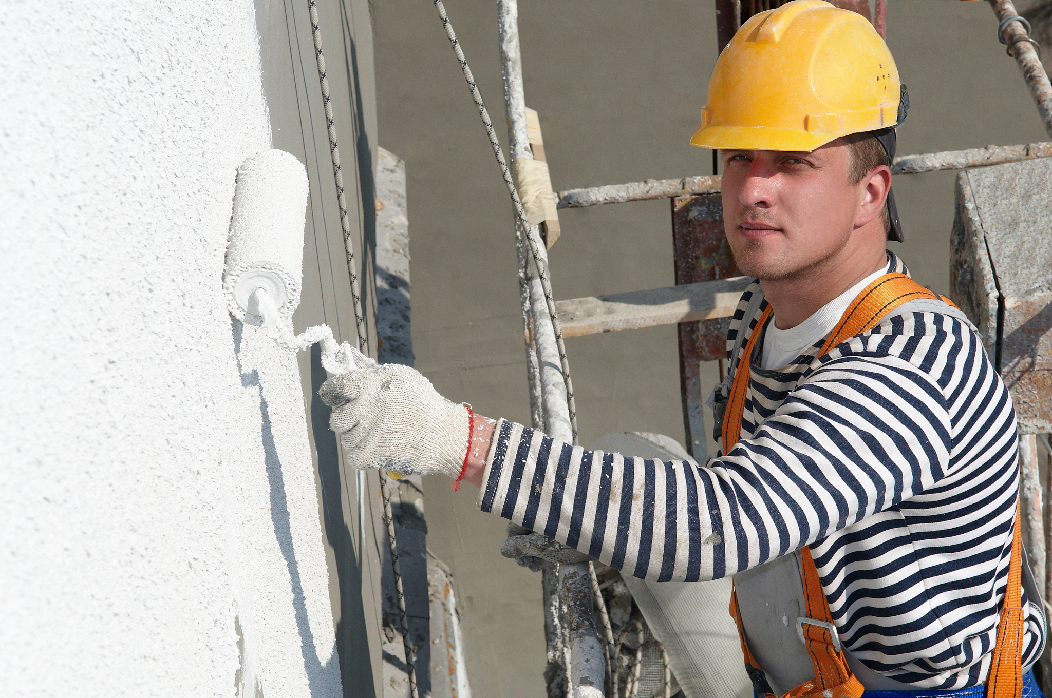 man on scaffolding painting the exterior of a building