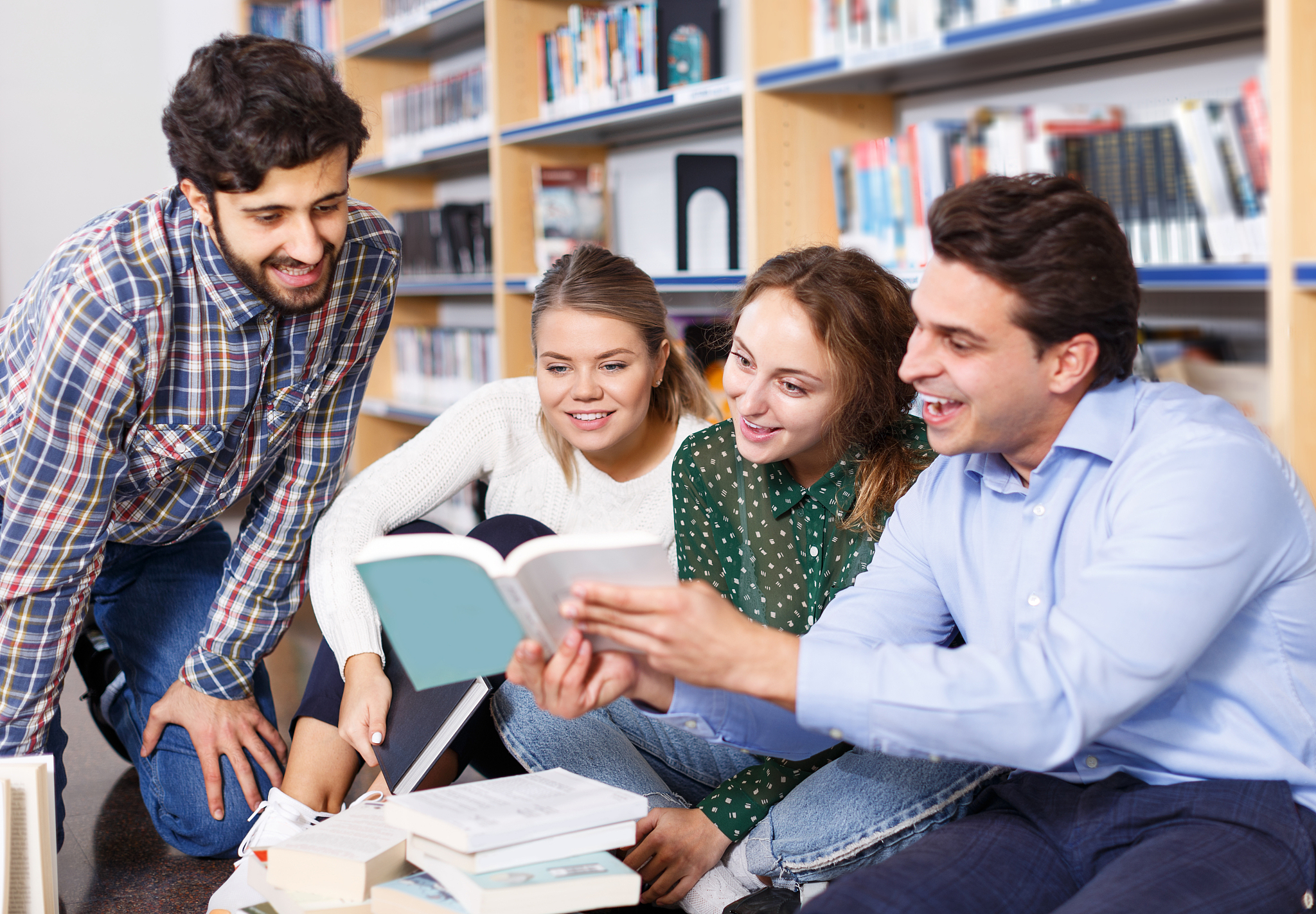 students sitting on floor in library in campus and preparing tog