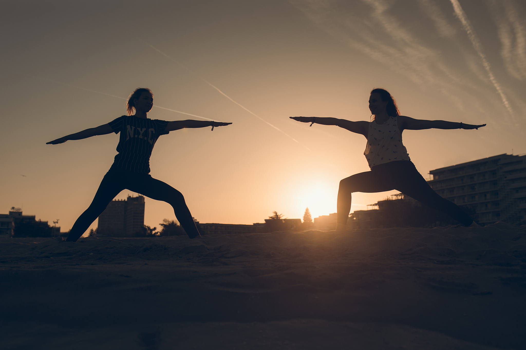 two women practicing yoga on the beach
