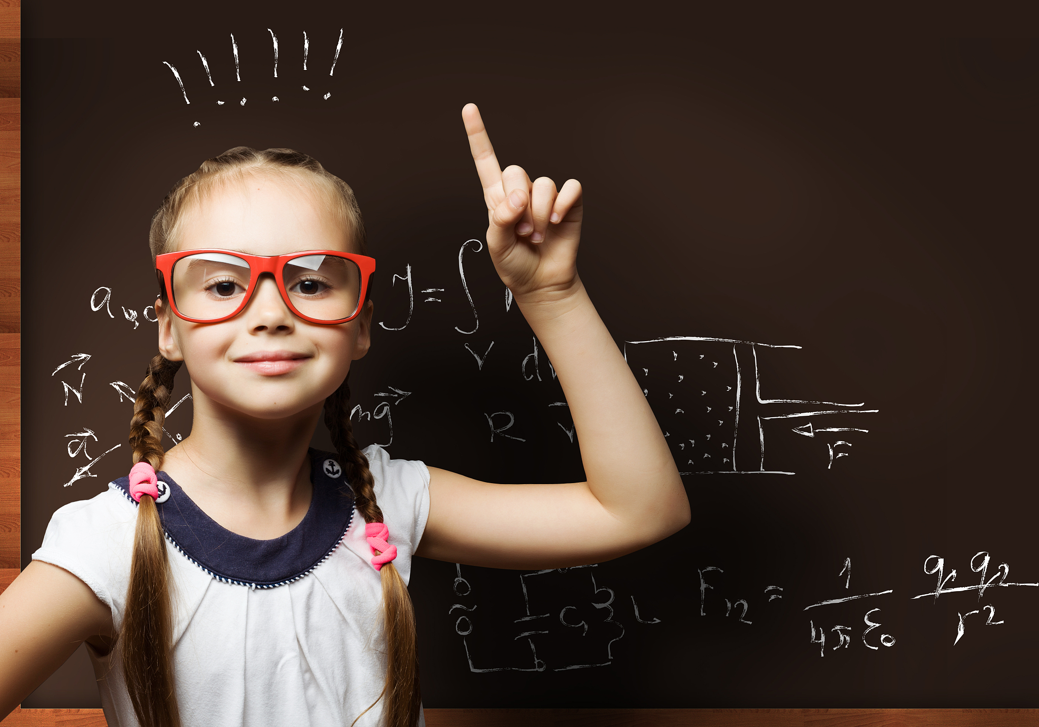 wunderkind. cute school girl in glasses standing at blackboard