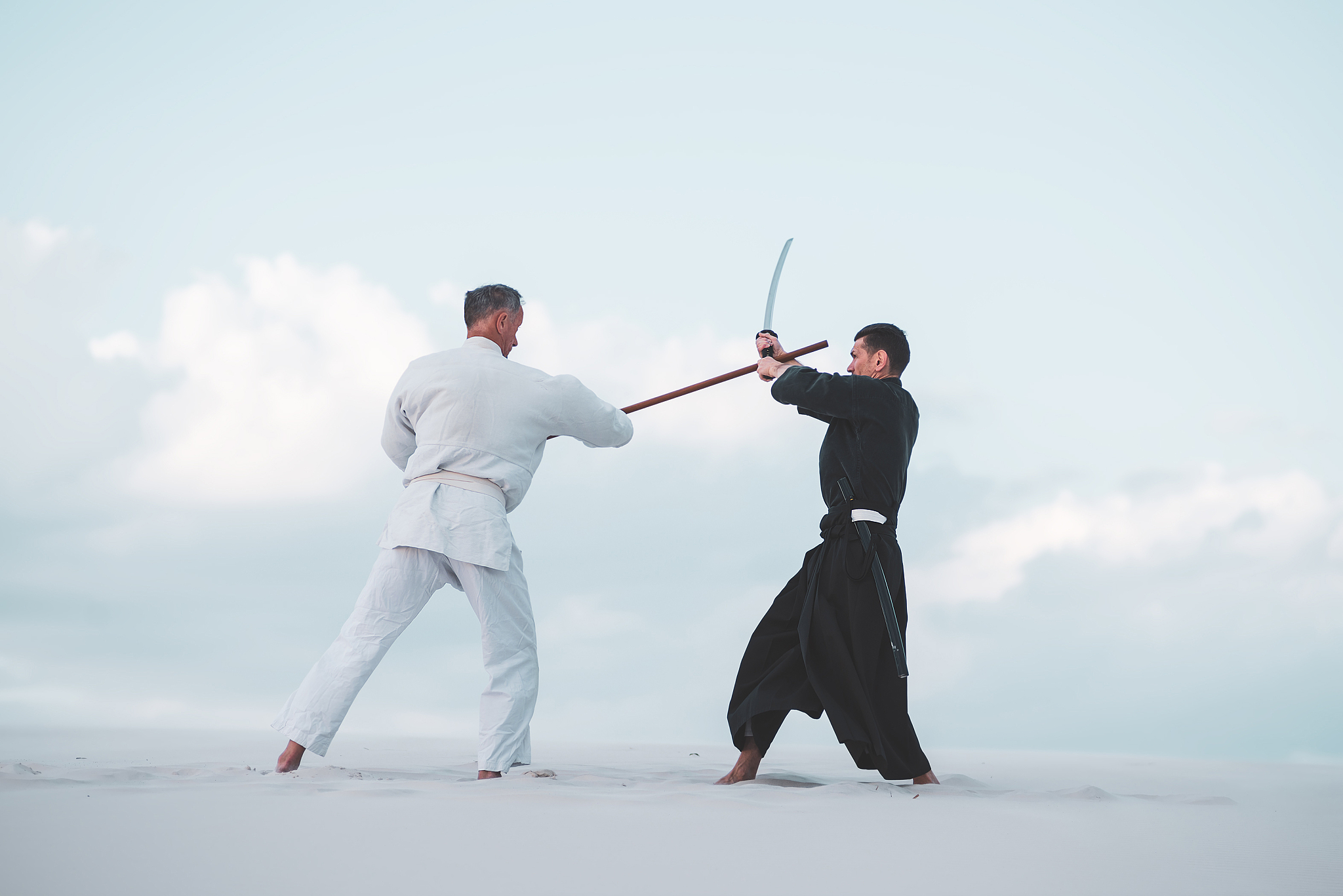 two men practicing japanese martial arts in desert