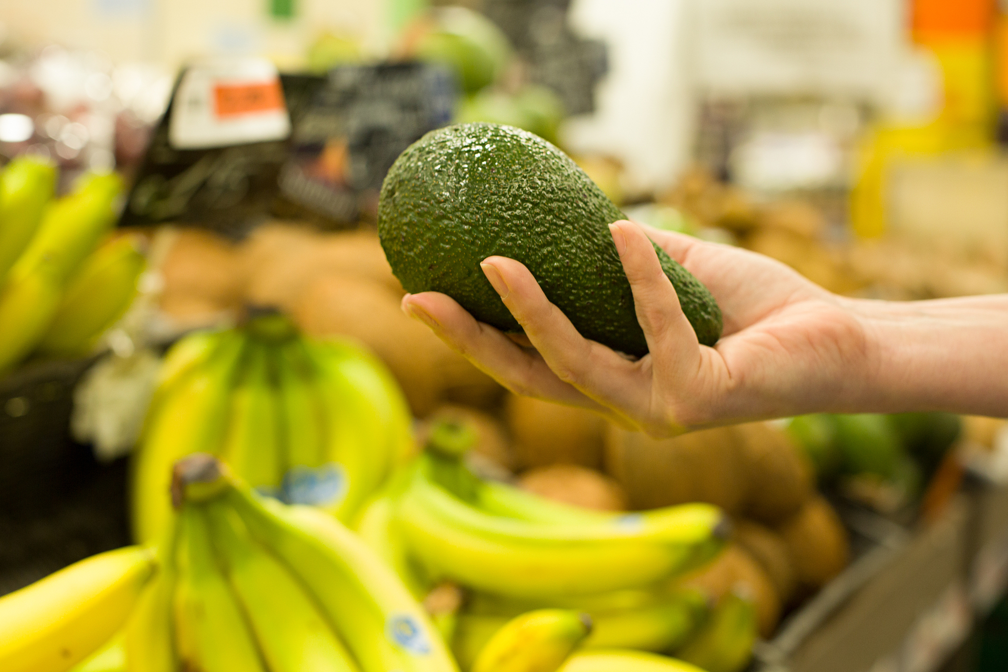 woman's hand choosing avocado in the market. concept of healthy 