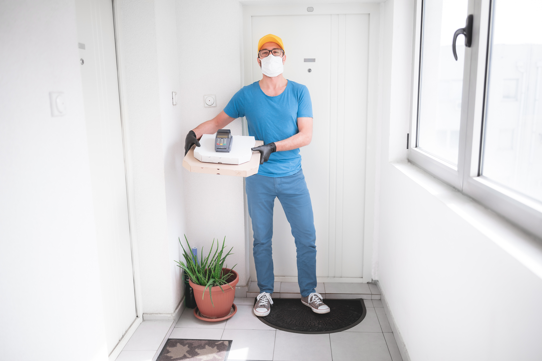 deliveryman with protective medical mask holding pizza box and p