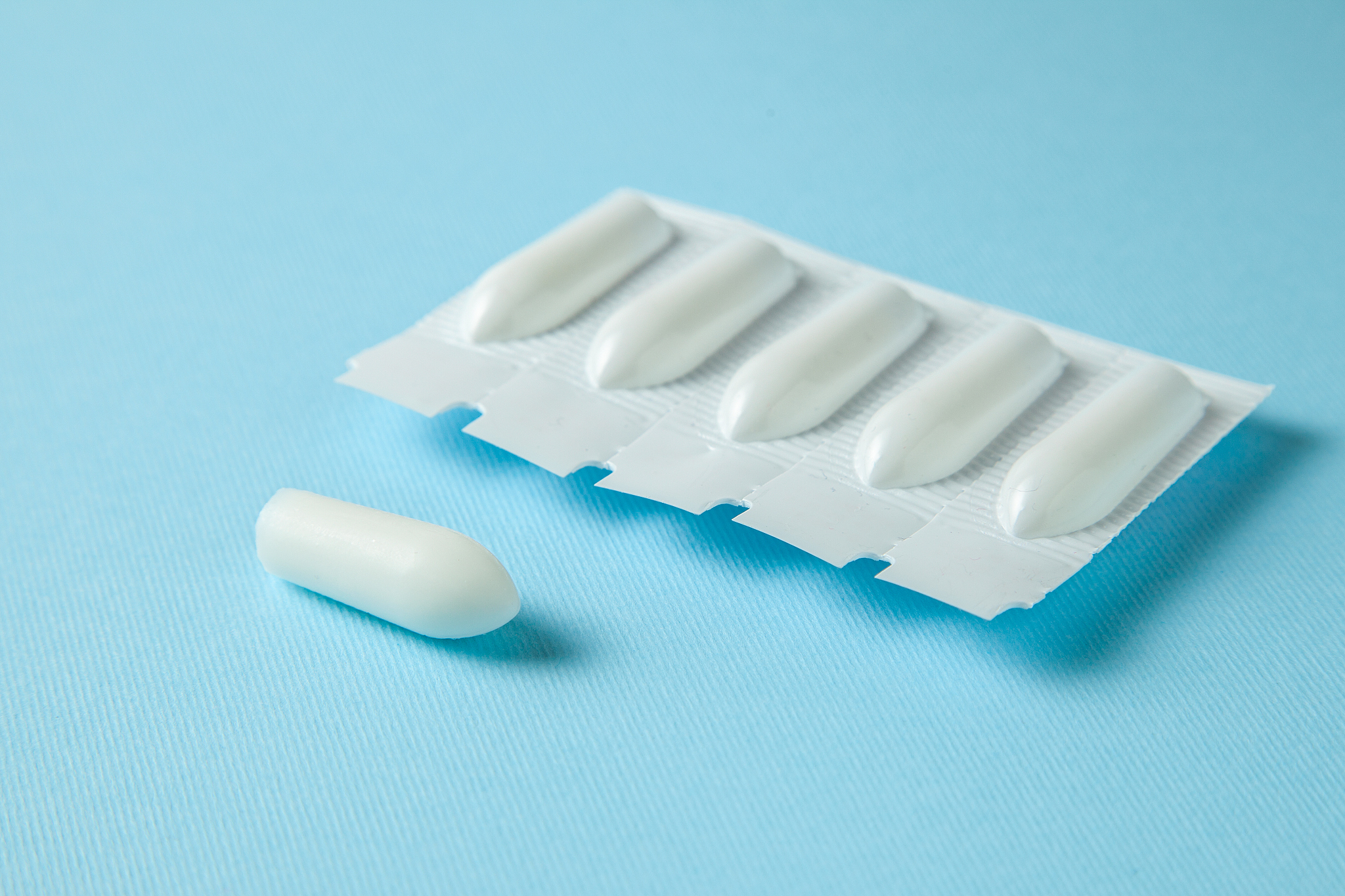 suppository for anal or vaginal use on a blue background. candle