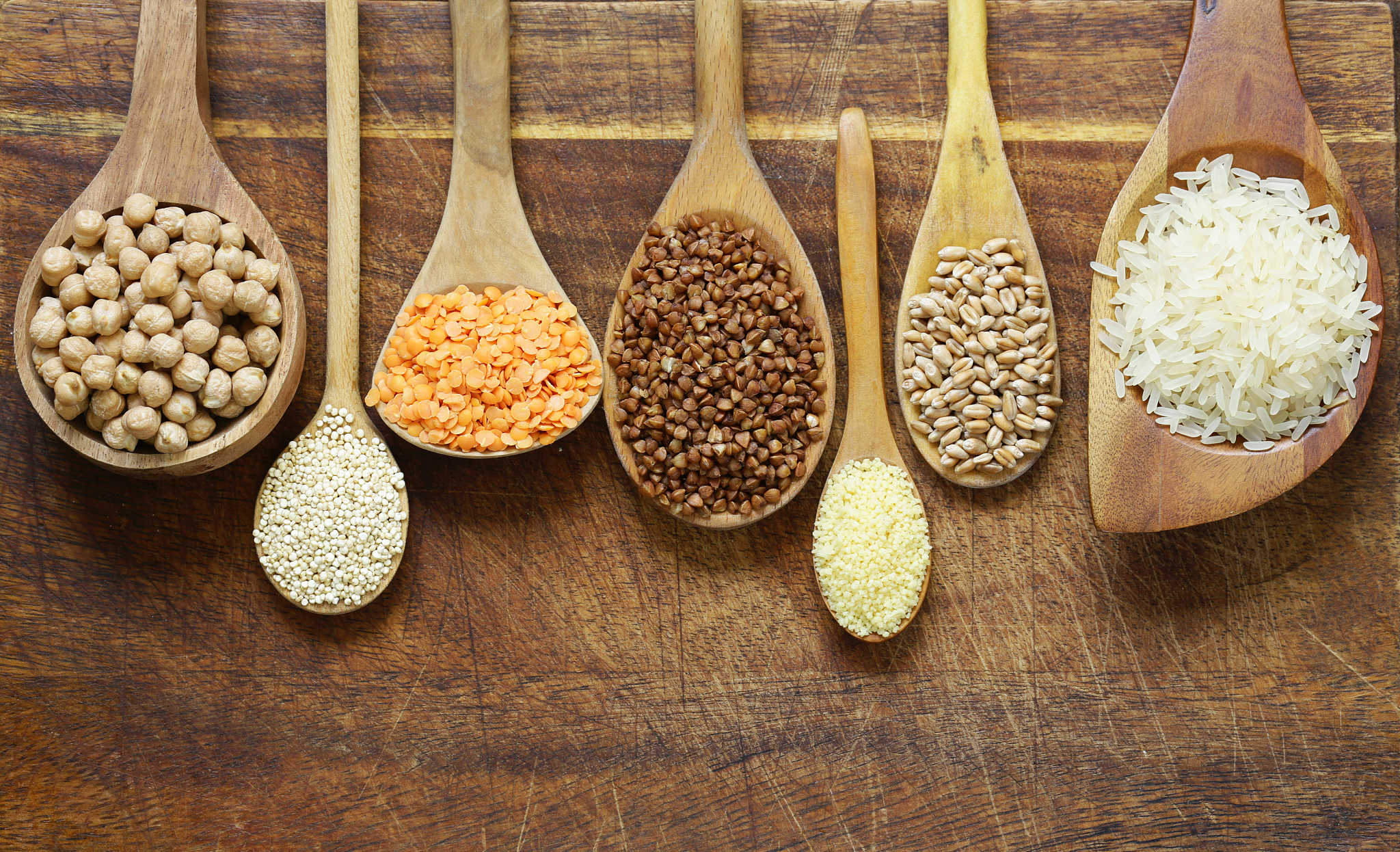 different types of cereals in wooden spoons - buckwheat, chickpe