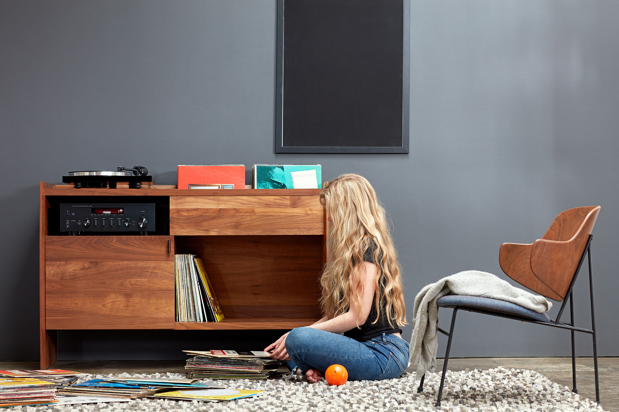 woman sorting through vinyl records by custom stereo cabinet