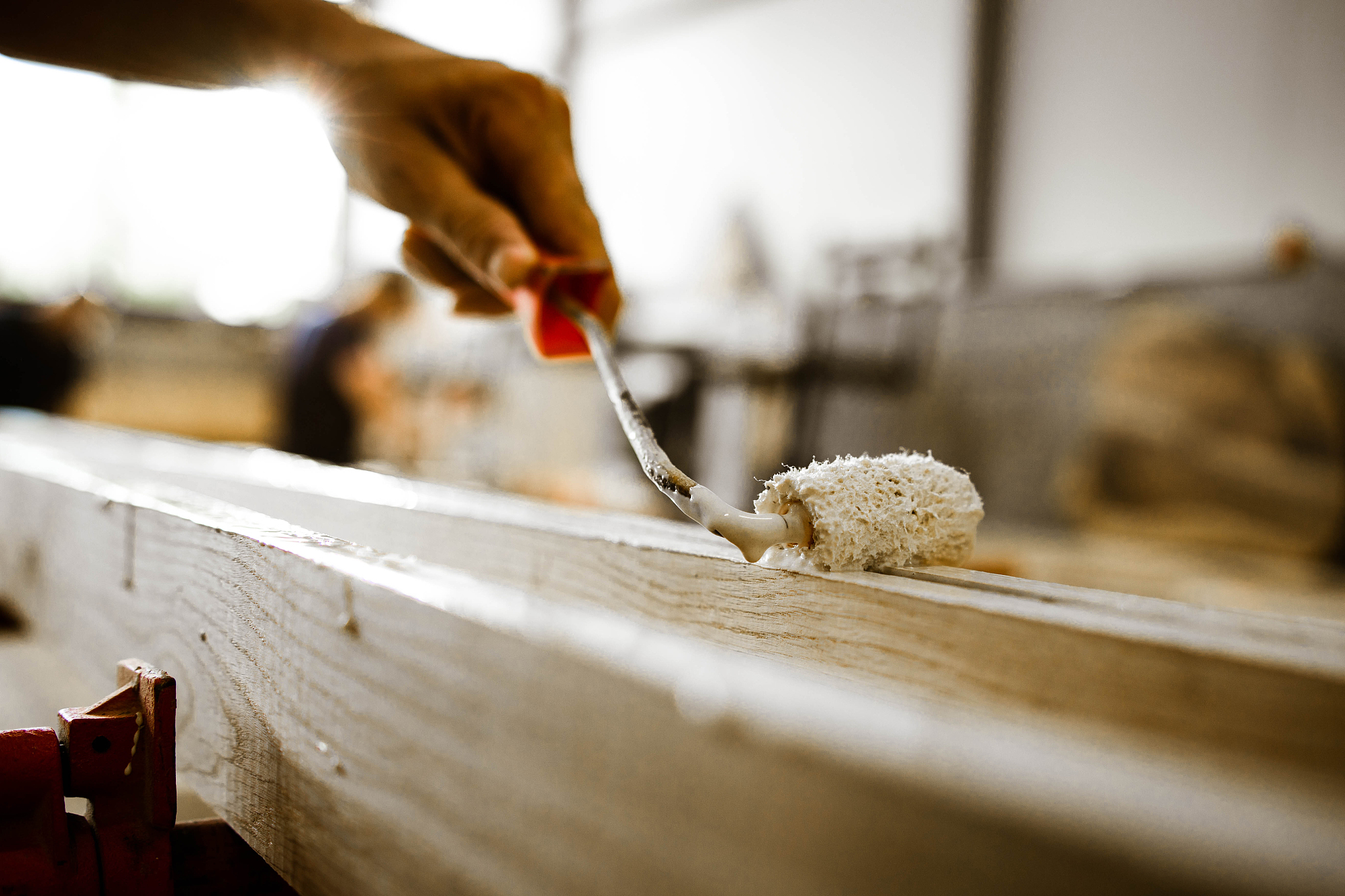 close up of painting wooden plank in a workshop.