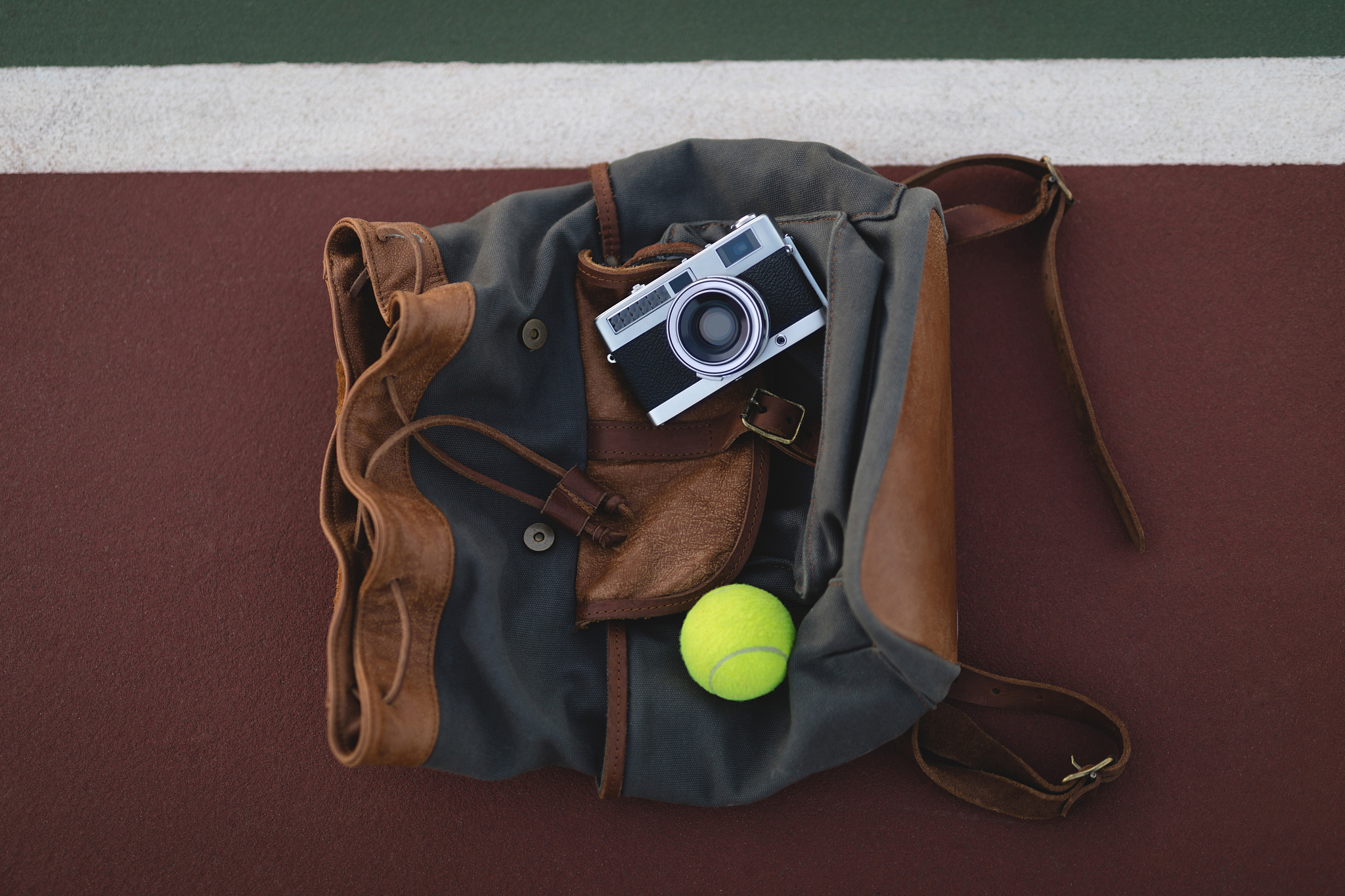 digital camera, tennis ball and bag on ground