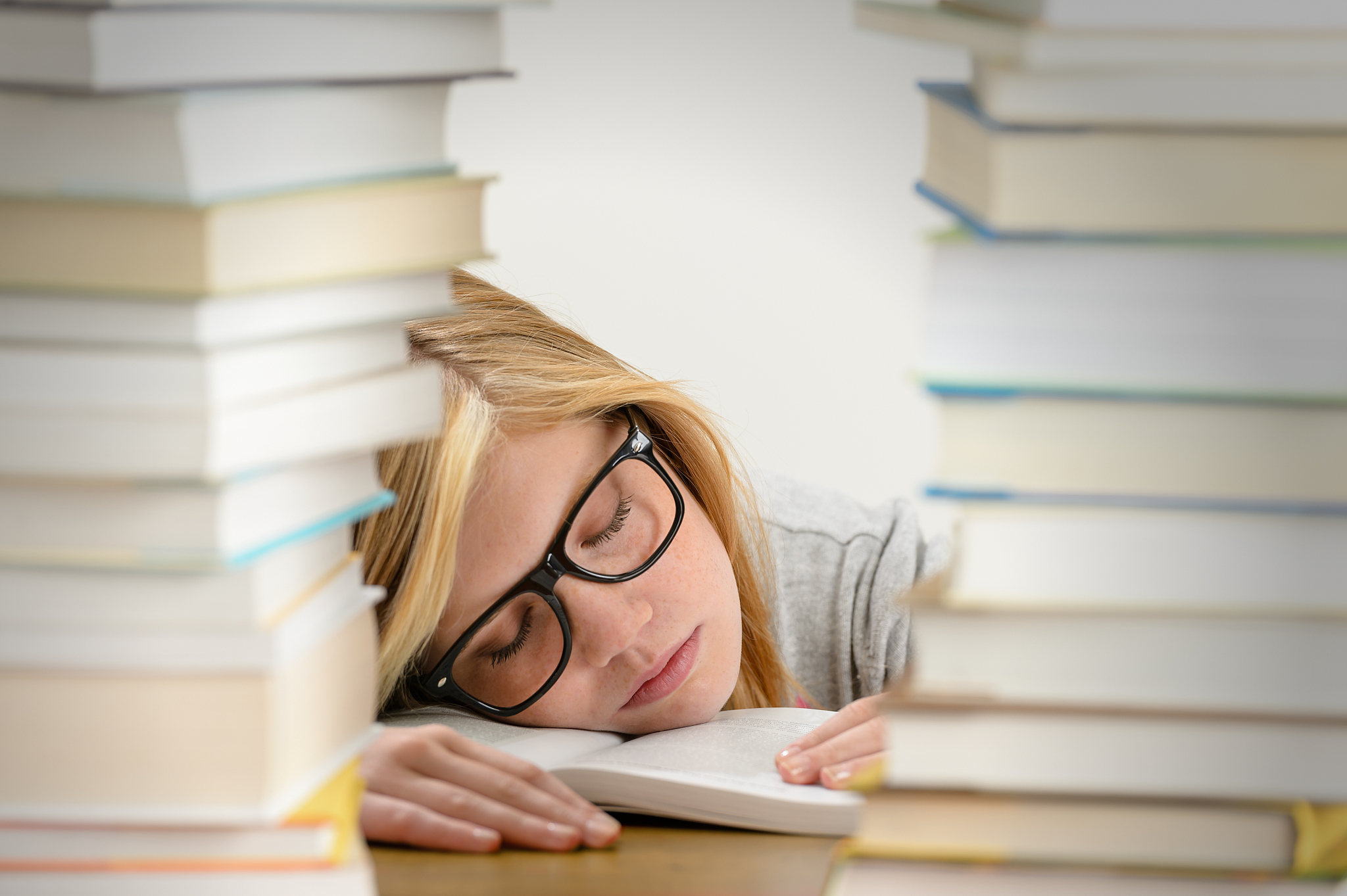 student girl sleeping between pile of books