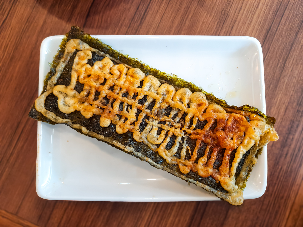 请根据以下模板写一份相似的文案描述更有画面感和诱惑力文字数量大致相同：就是这个芝士热狗饭团让我家不爱吃米饭的儿子都炫了三个昨晚吃剩的米饭倒入碗中加适量盐五滴香油用我的手抓匀备用锅中油热下香肠煎至焦香即可准备一块海苔撕成两半铺上2块芝士片放上小孩爱吃的香肠再像我这样卷起来尾部用米饭粘合后放入碗中备用大米饭用手按压开再放入海苔给它包起来锅中油热放饭团再给饭团均匀的刷上调好的酱汁一面刷好后再刷另一边煎至