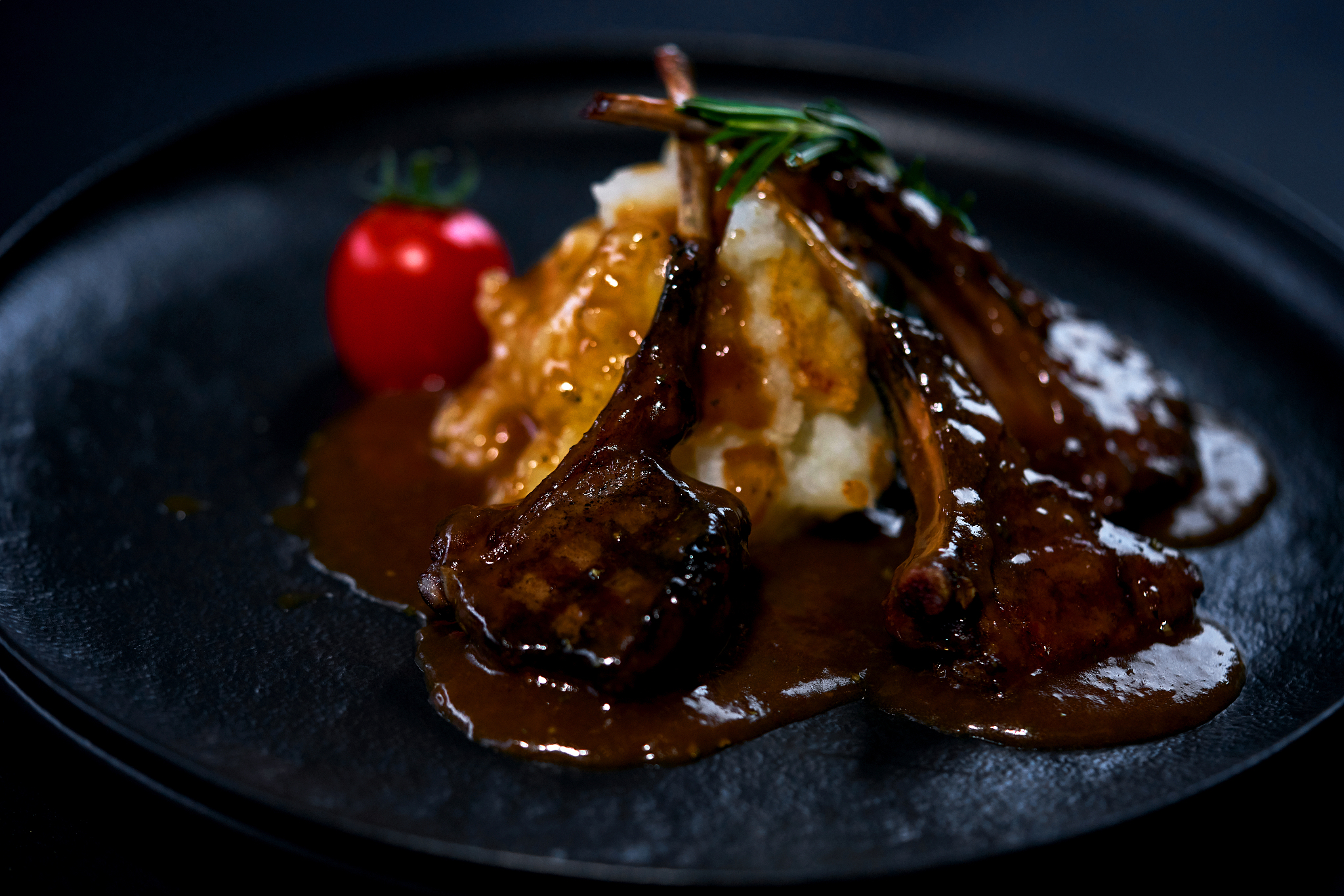 rack of lamb on a black plate with garnish