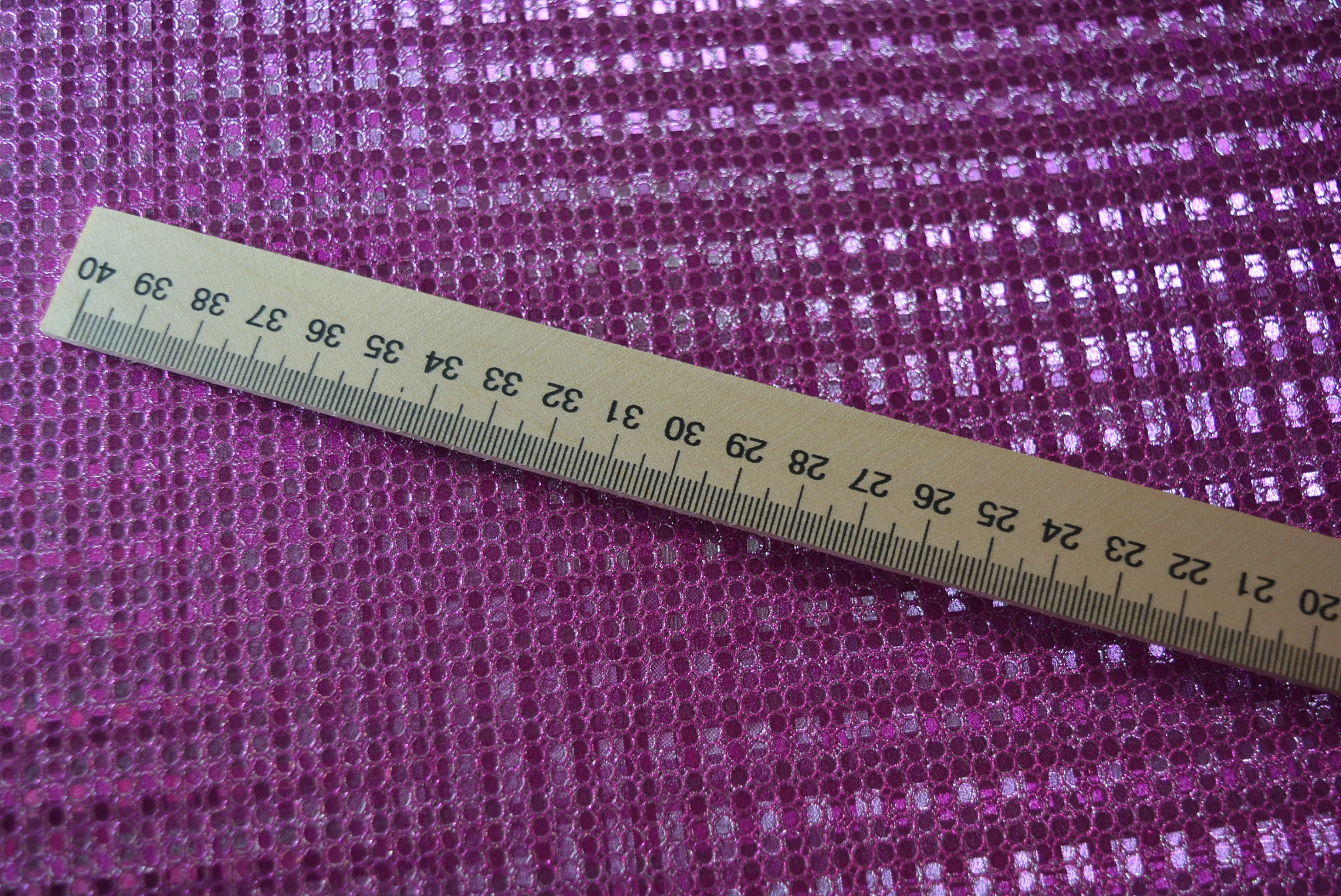 light wooden mathematical ruler on a pink reflective background.