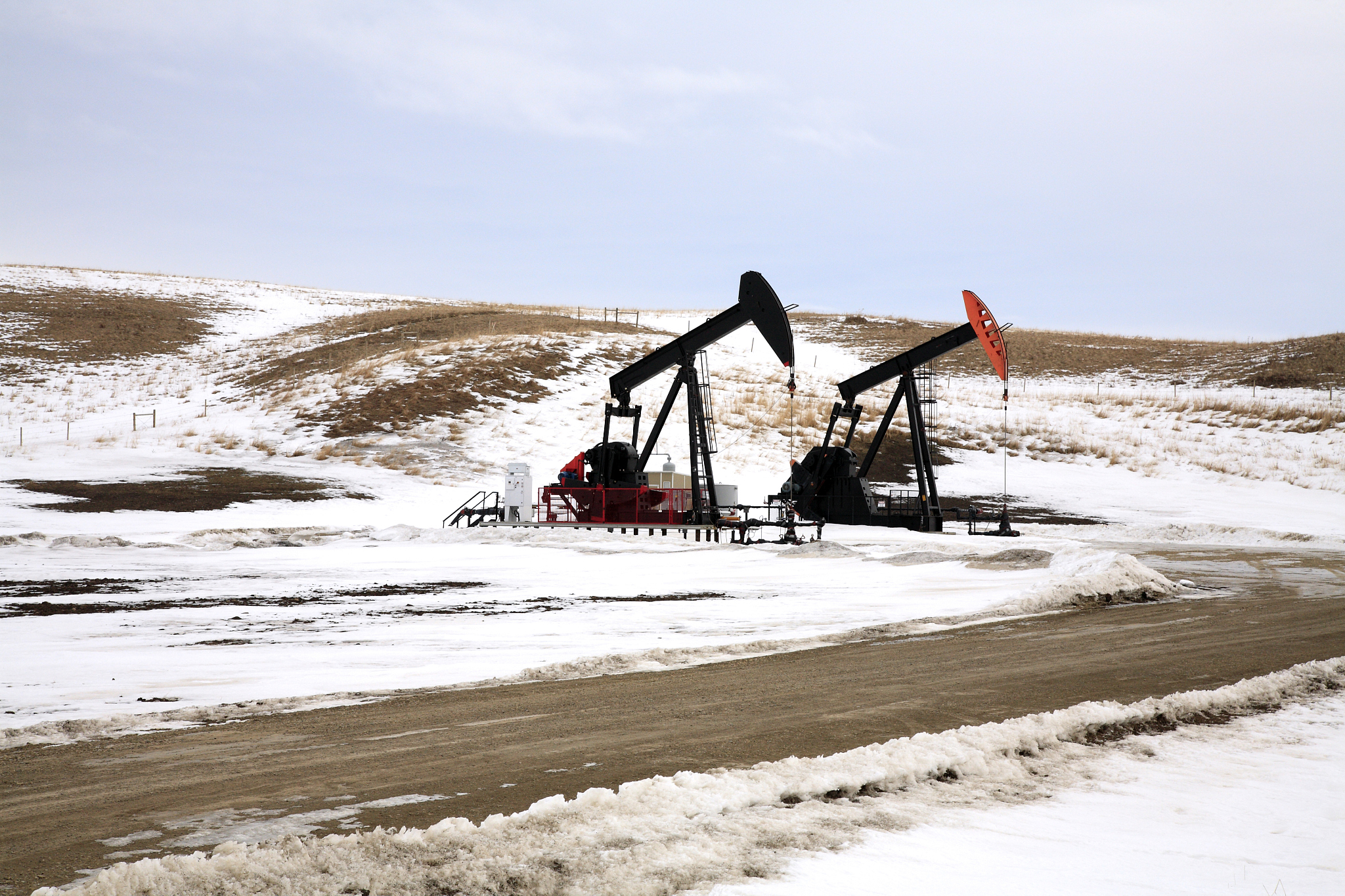 two pump jacks drilling on winter grasslands