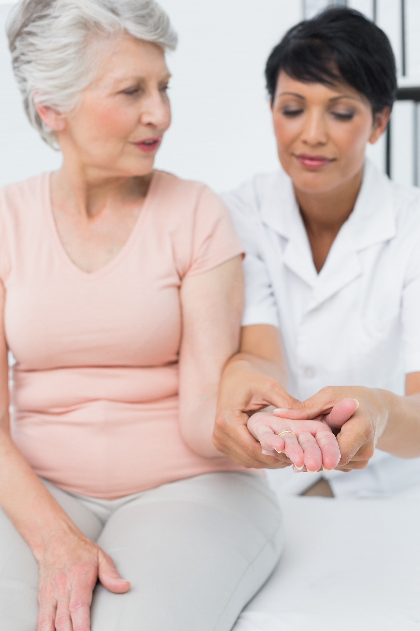 female physiotherapist examining a senior patients hand