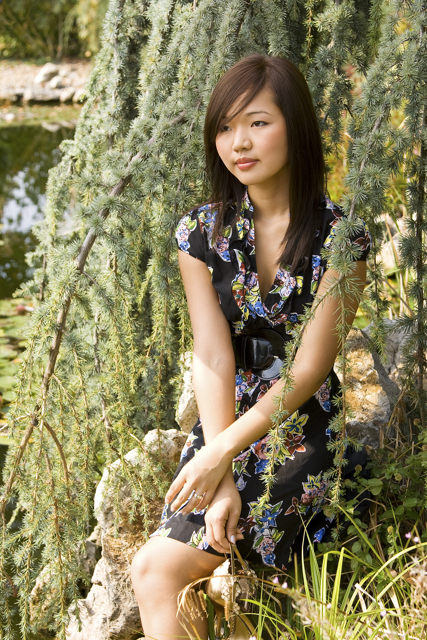 brunette asian girl sitting at the lakeside.
