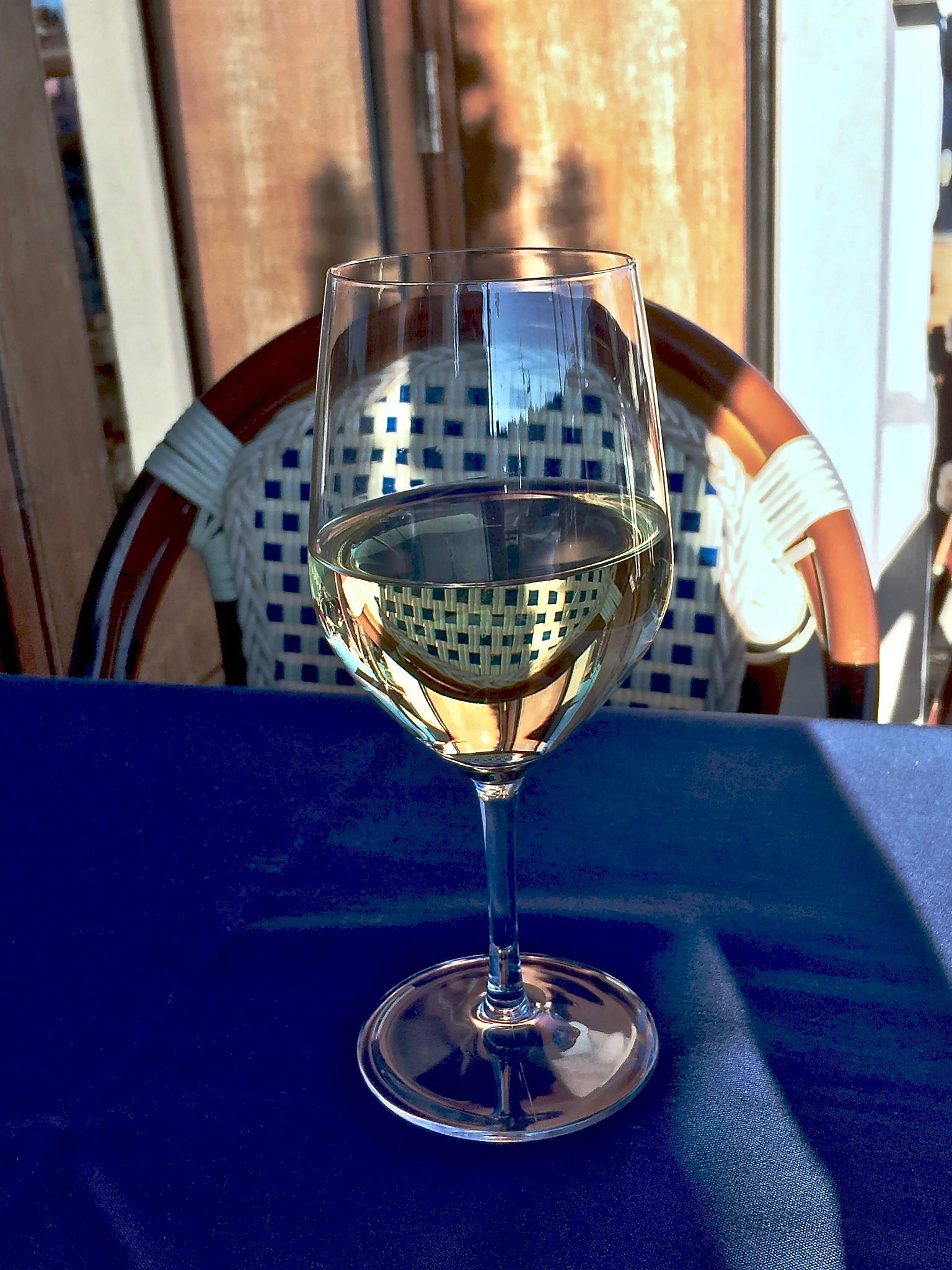 a glass of retsina wine on a table at an outdoor sidewalk restau