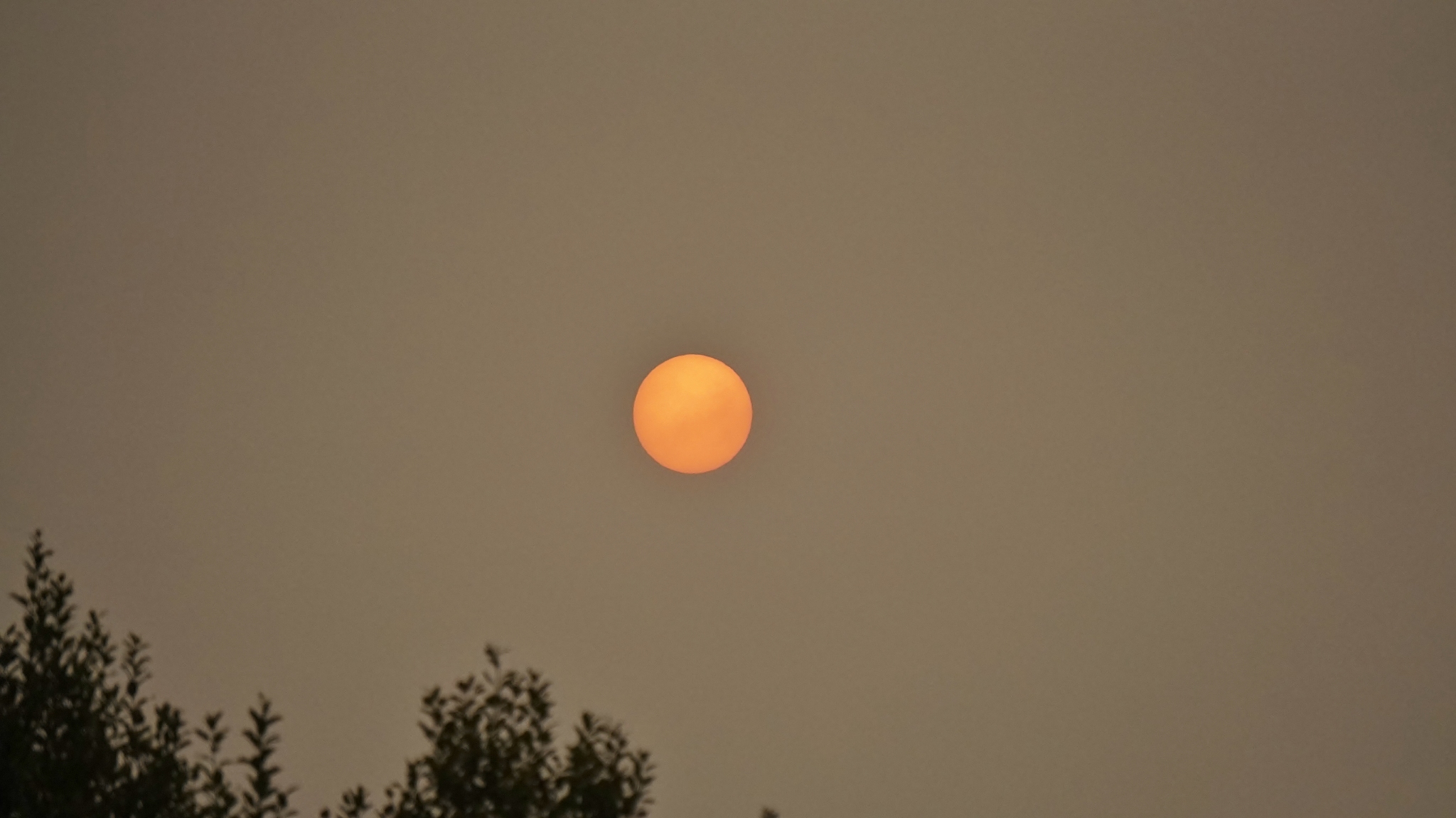 round orange sun on a grey day in corby, northamptonshire