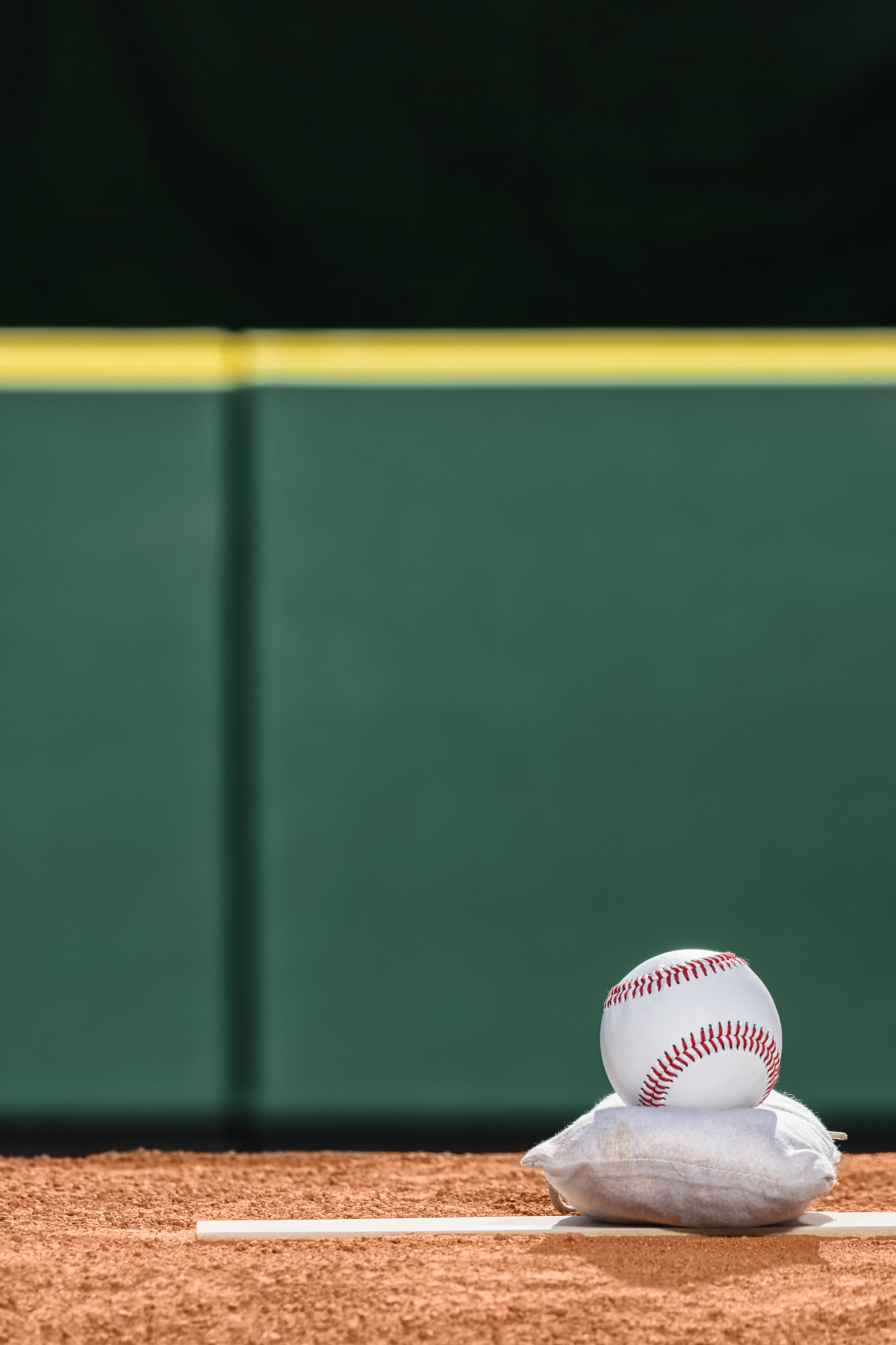 a new baseball sitting atop a rosin bag on pitcher's mound