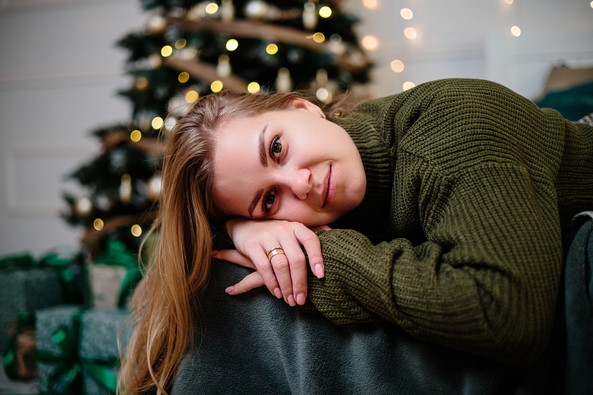 一位金发美女在新年的氛围中,坐在圣诞树旁欢庆.她身,