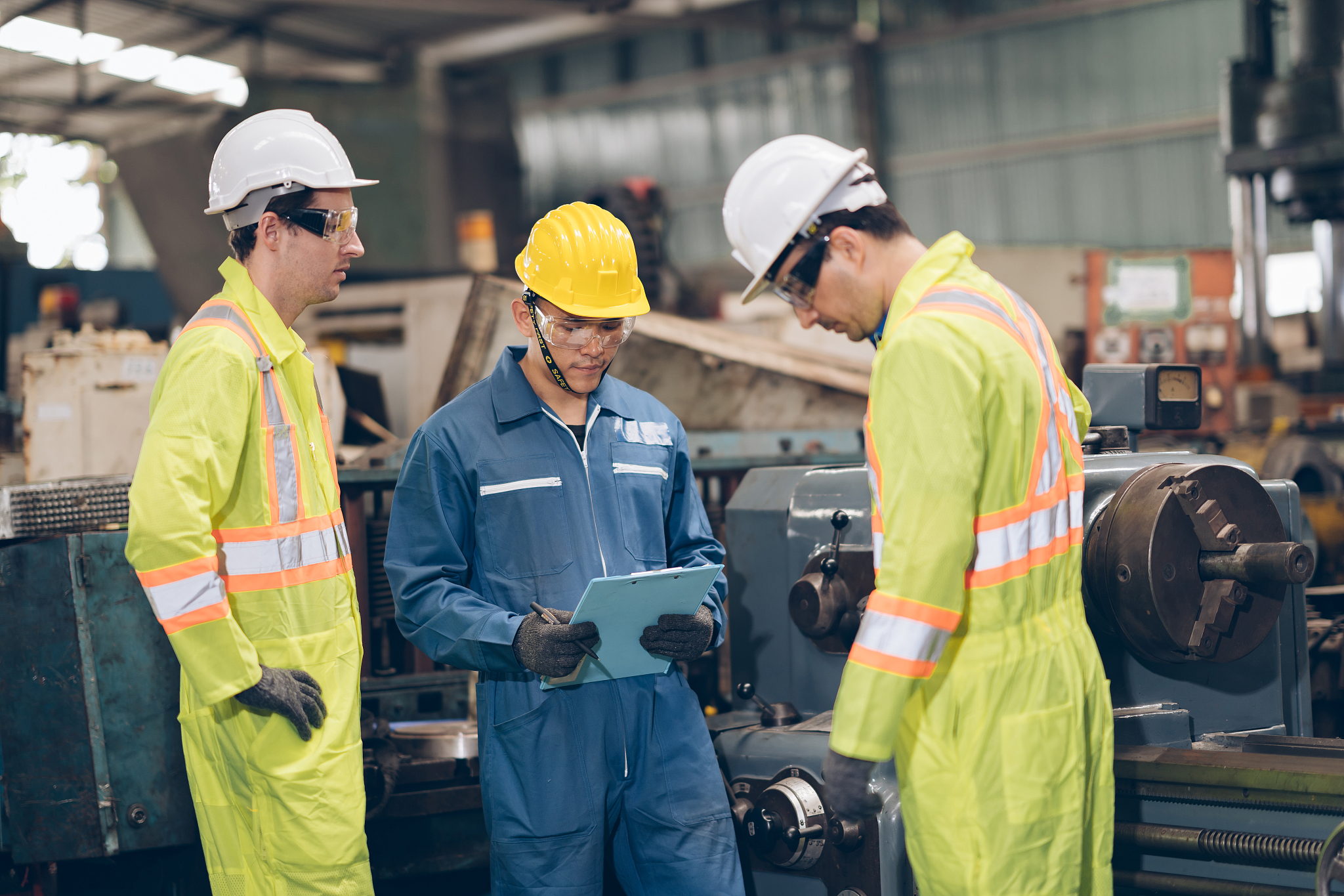 three technician mechanic working on machine in factory