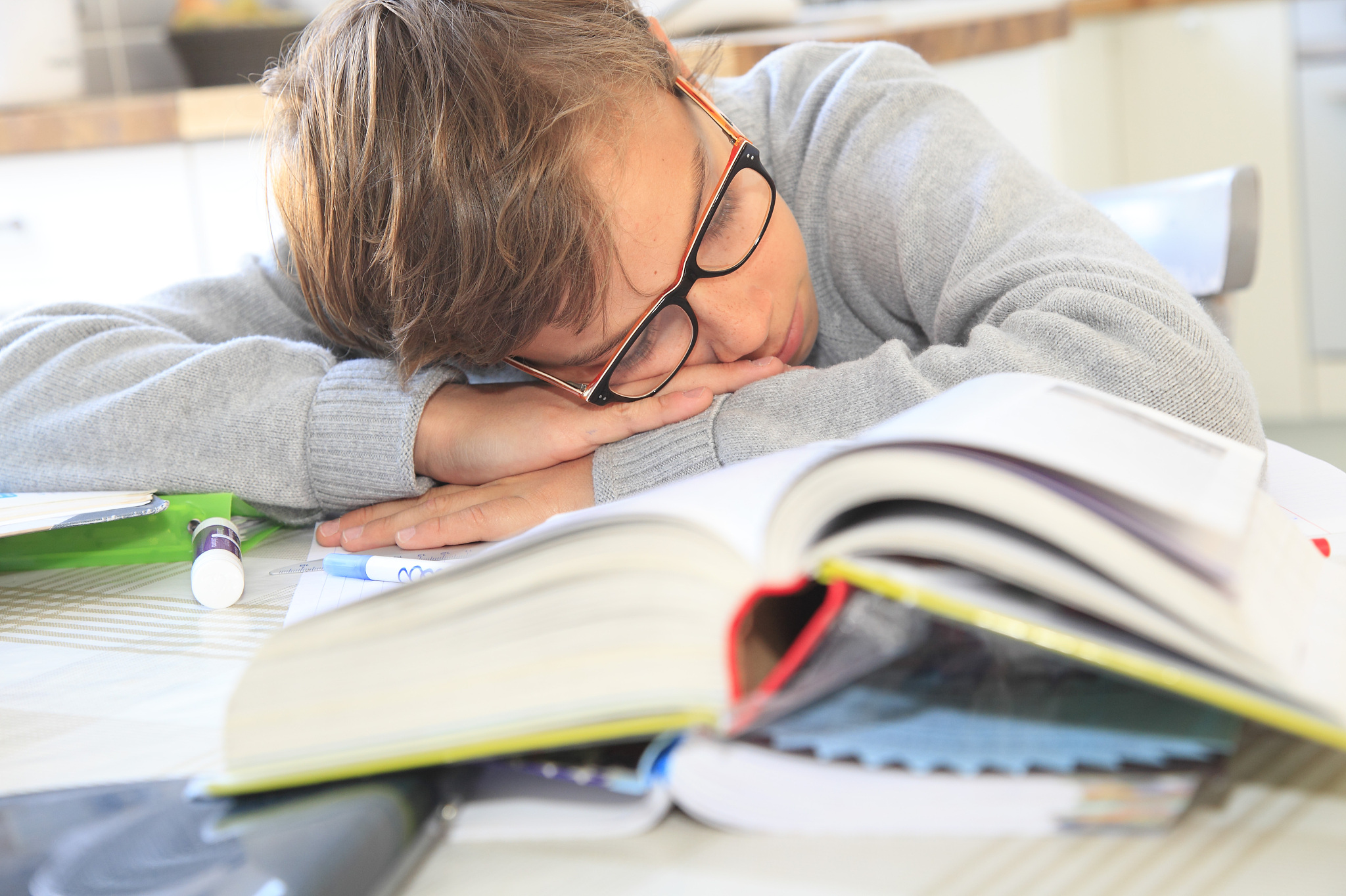 france, teenager sleeping on his lessons at home.