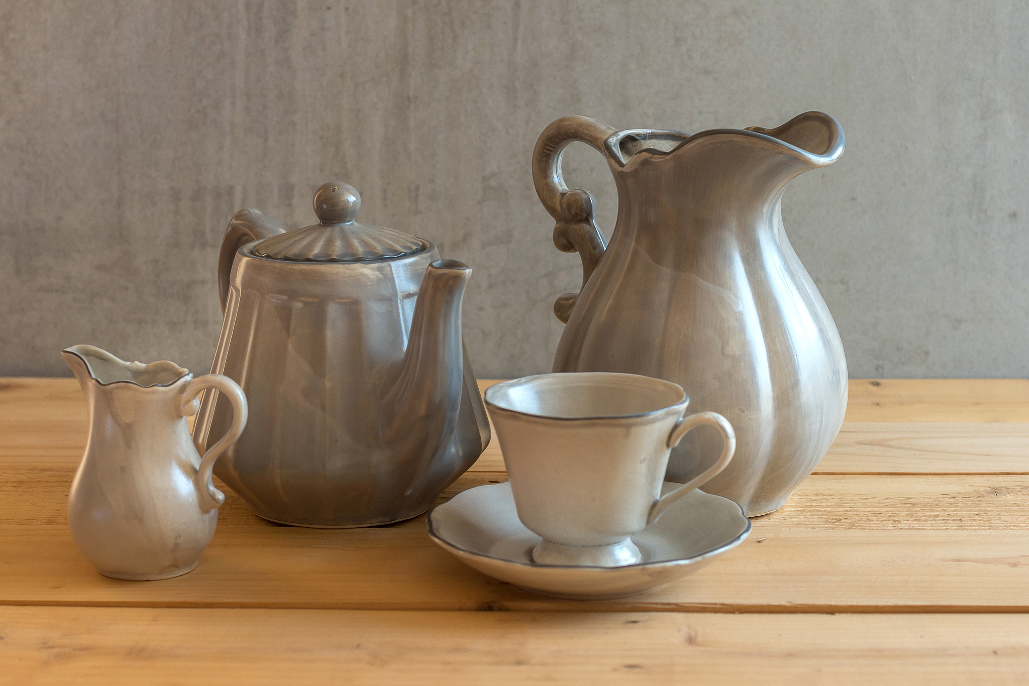 tea set is gray on a wooden background. teapot, creamer, cup and