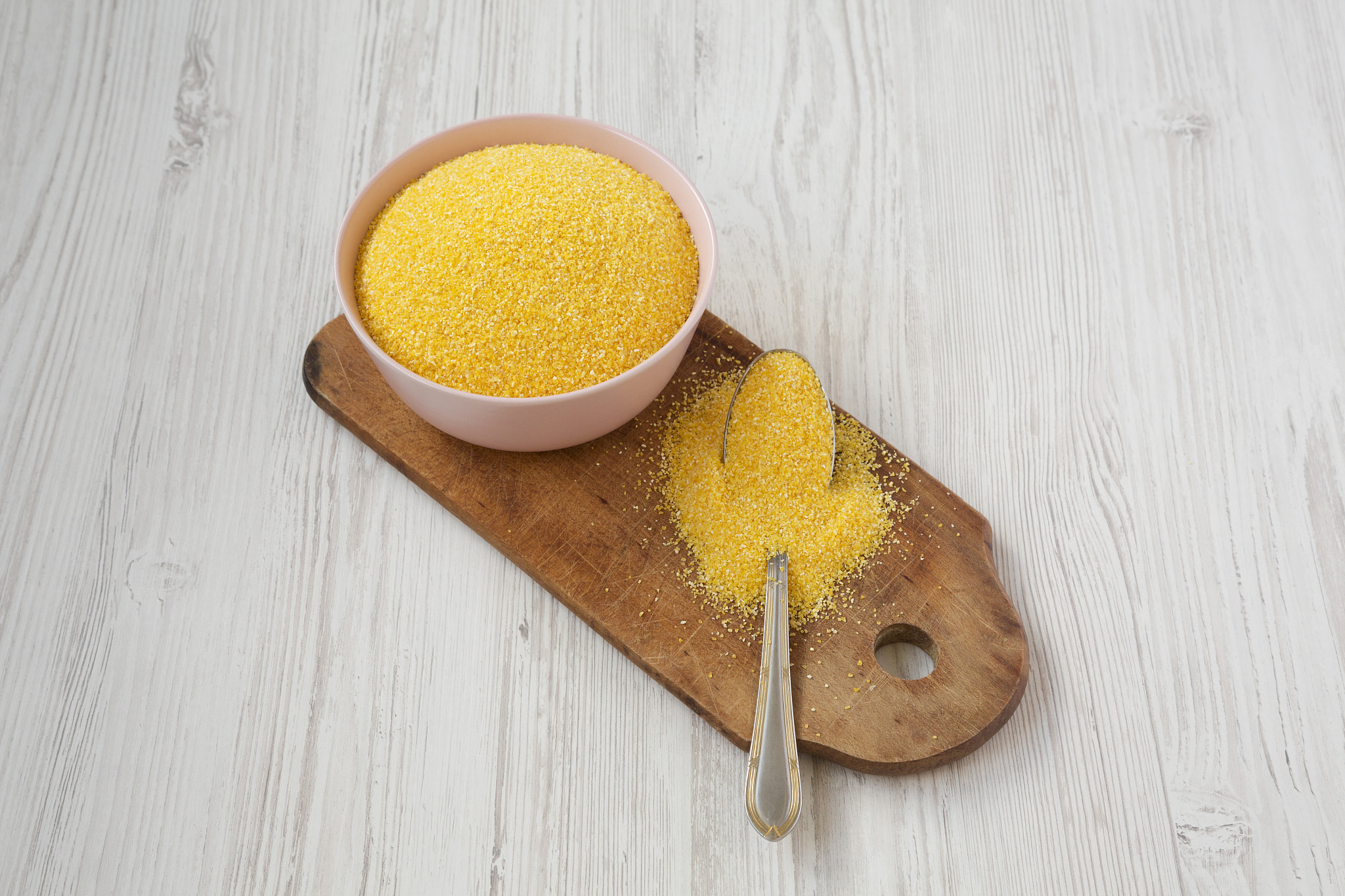 organic masarepa corn meal in a pink bowl over white wooden surf