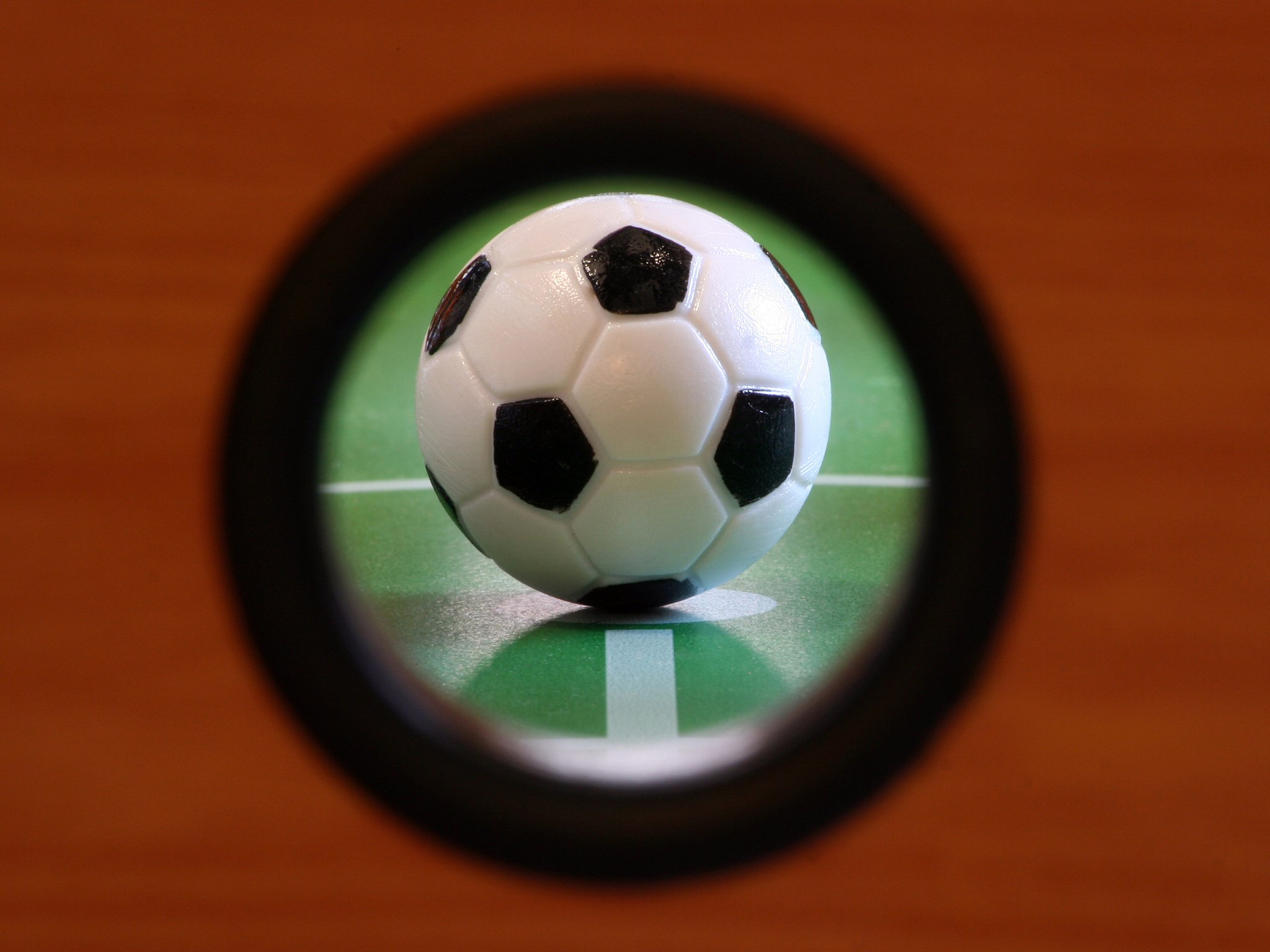 ssoccer ball on fussball table, seen throuhg hole in sidepanel