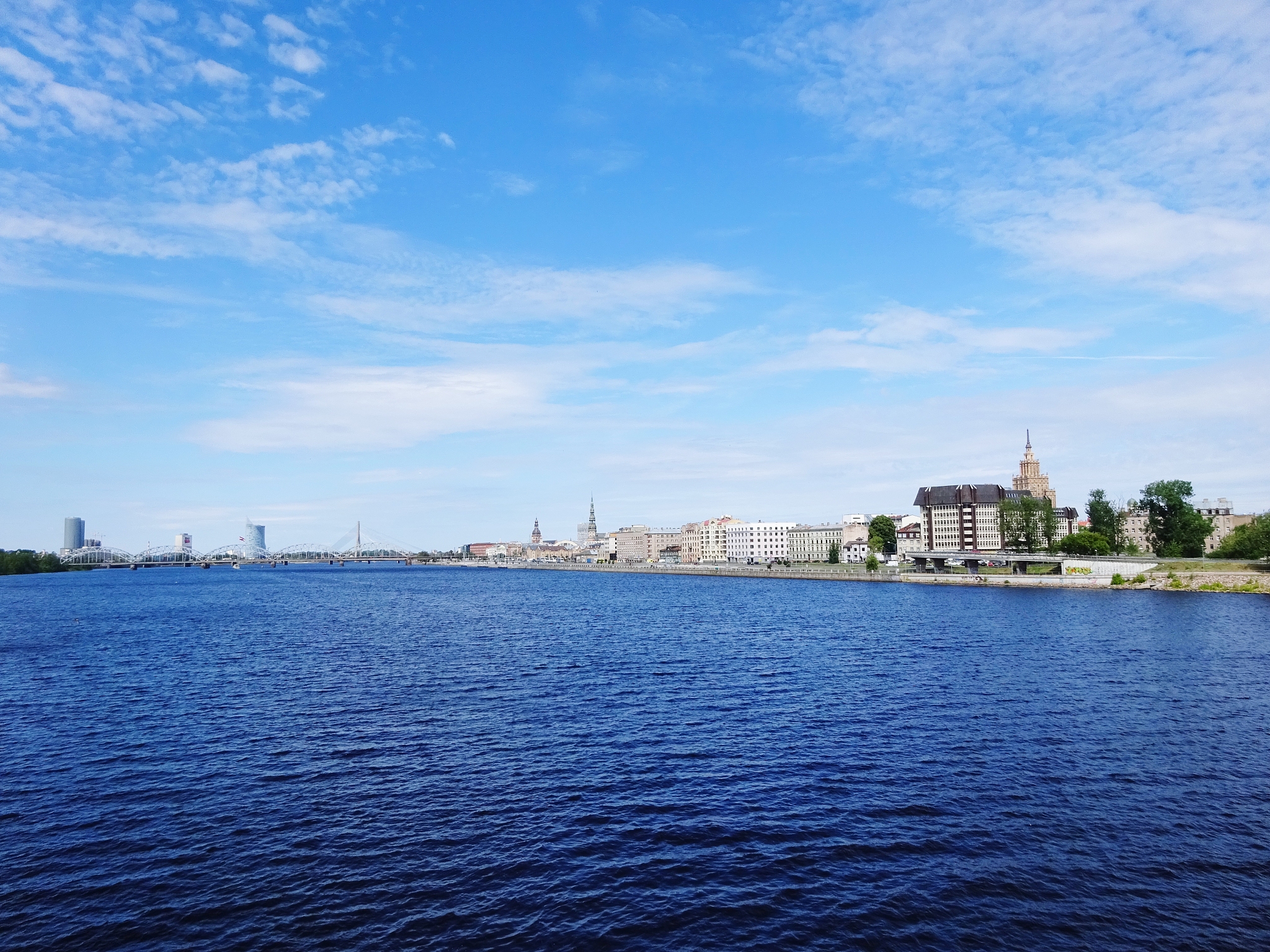 view of buildings by river against blue sky