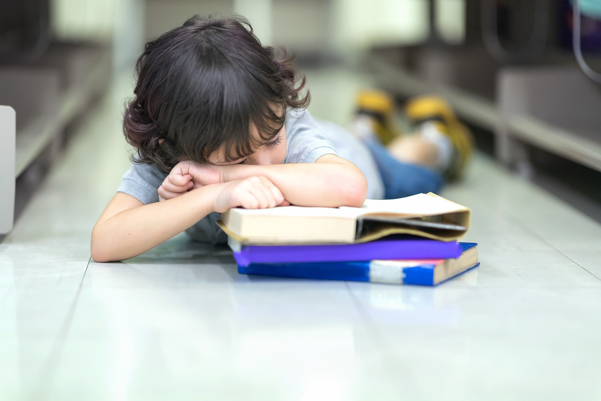 little boy has bored to study and sleeping on the book stack.