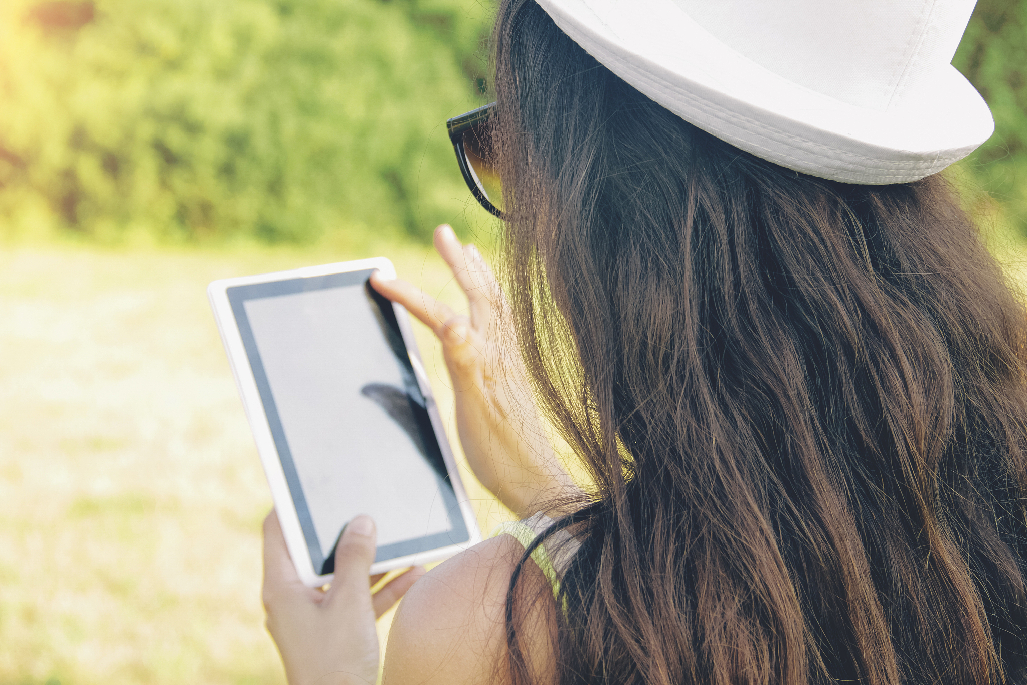 woman holds digital tablet, summer landscape