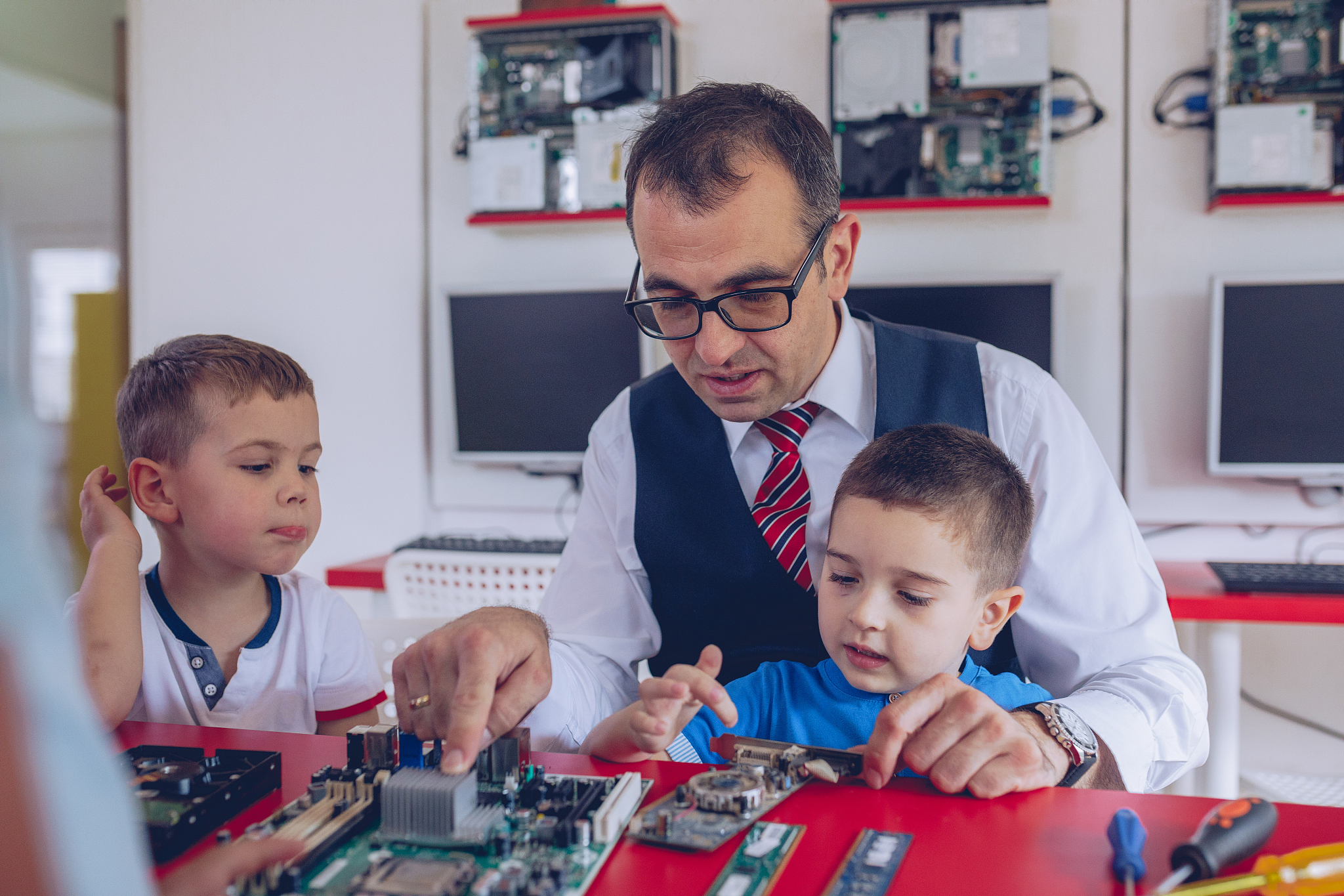 boys and teacher repairing computer hardware