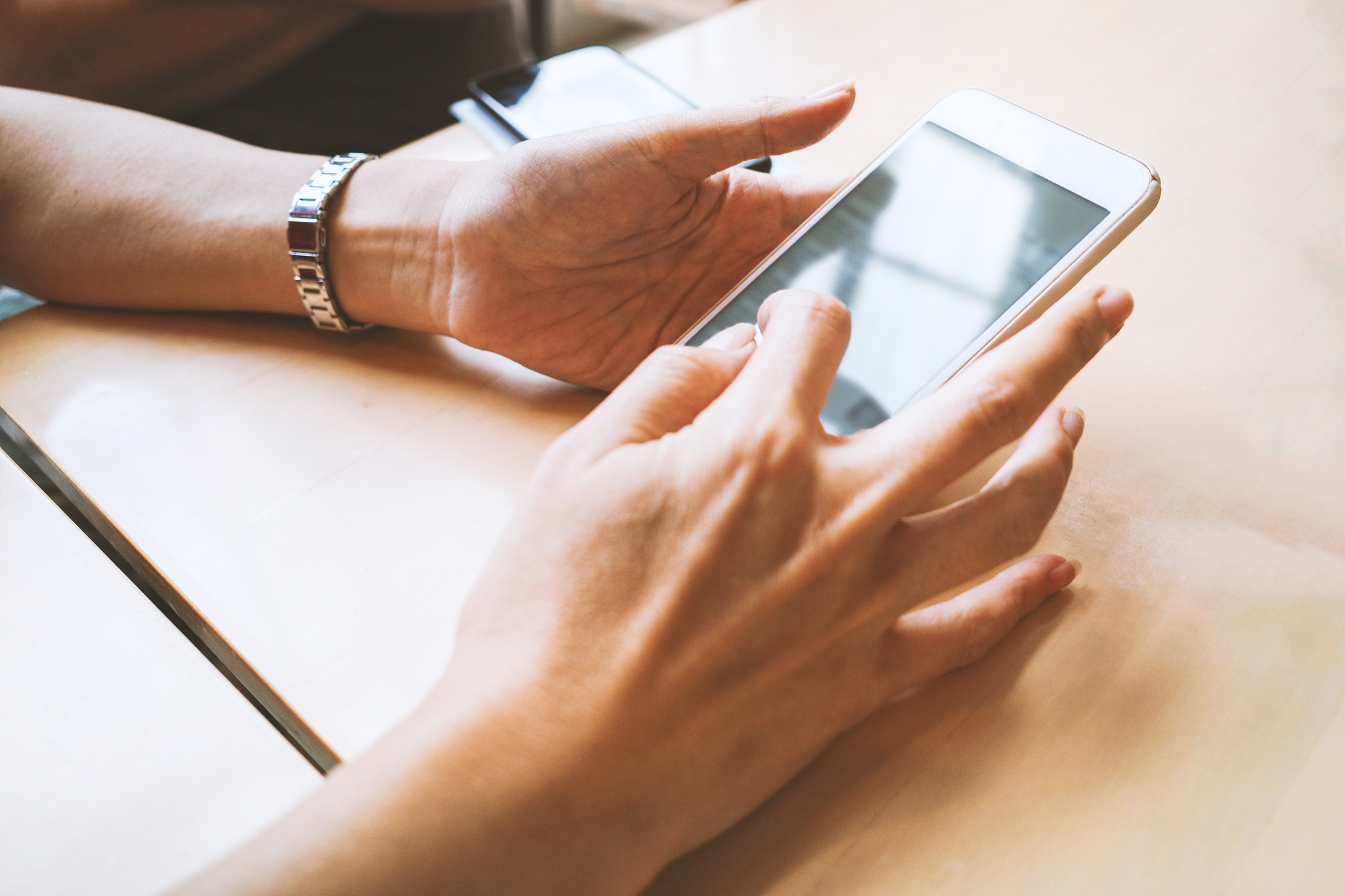 close-up of hand using mobile phone on table