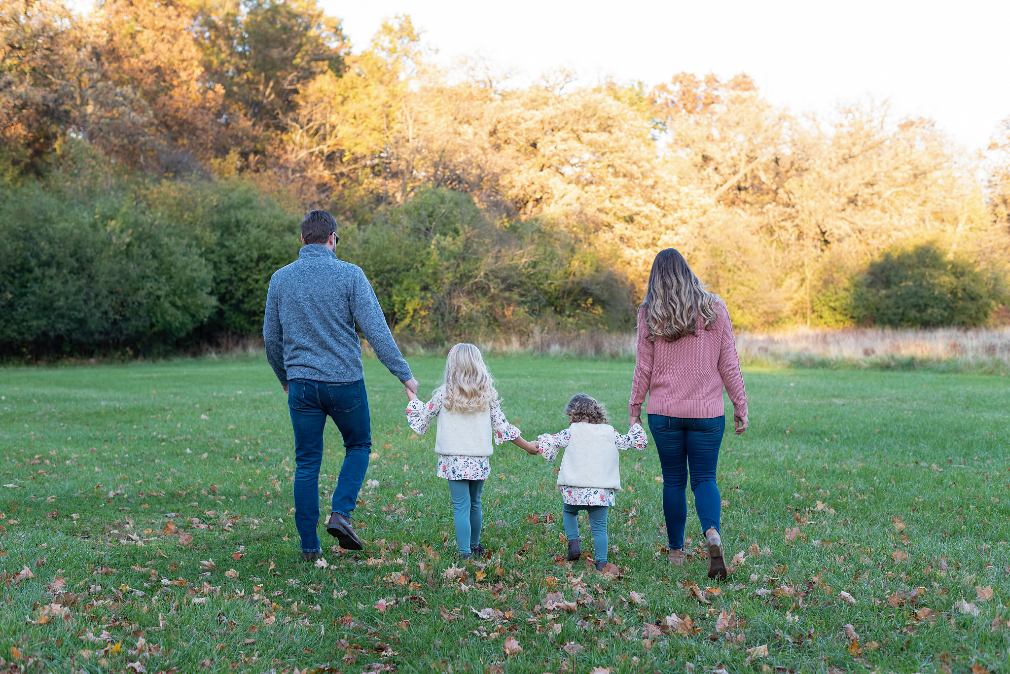 rear view of friends standing on grass against trees