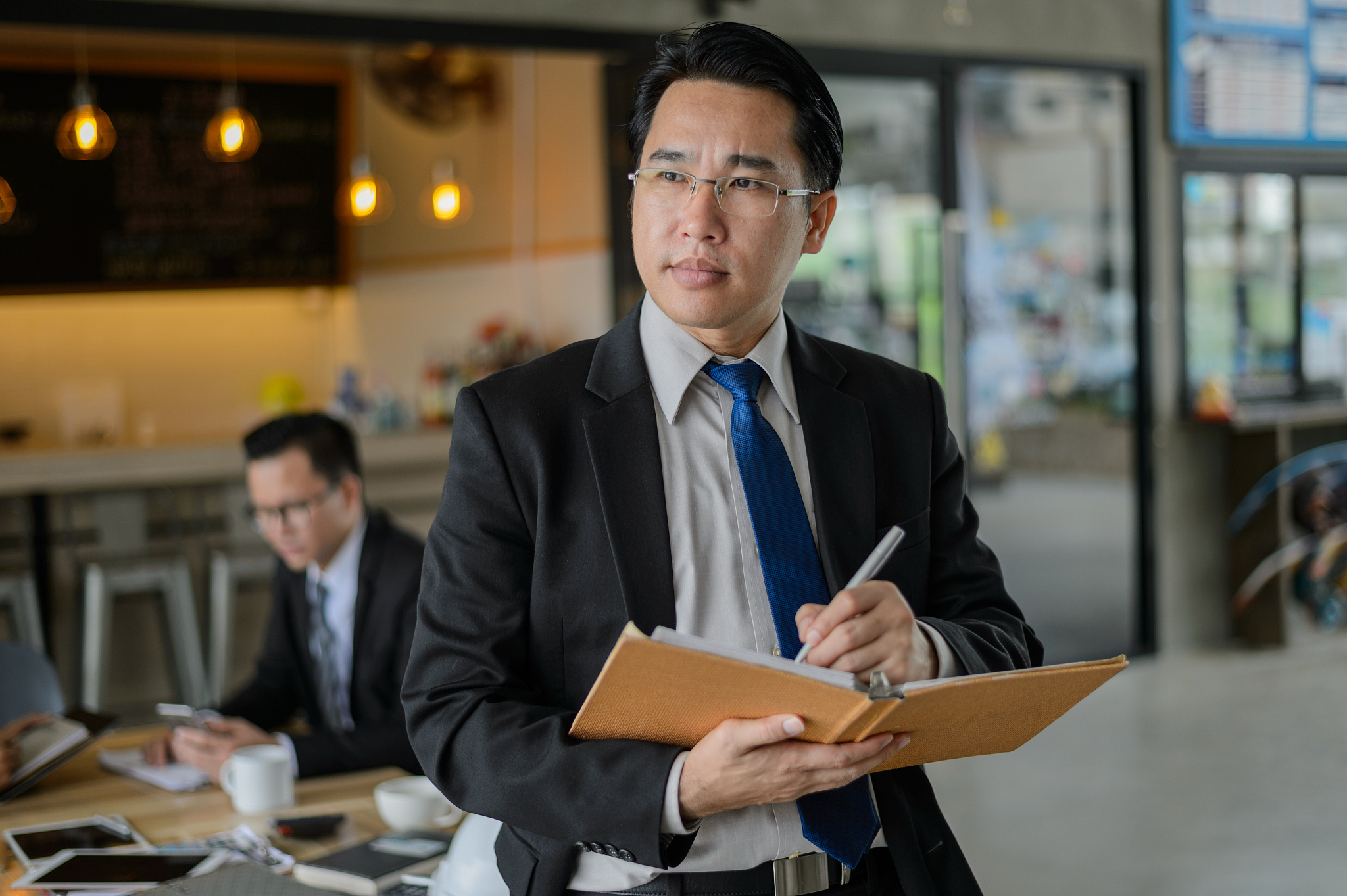 asian businessman holding a book and pen to write a business pla