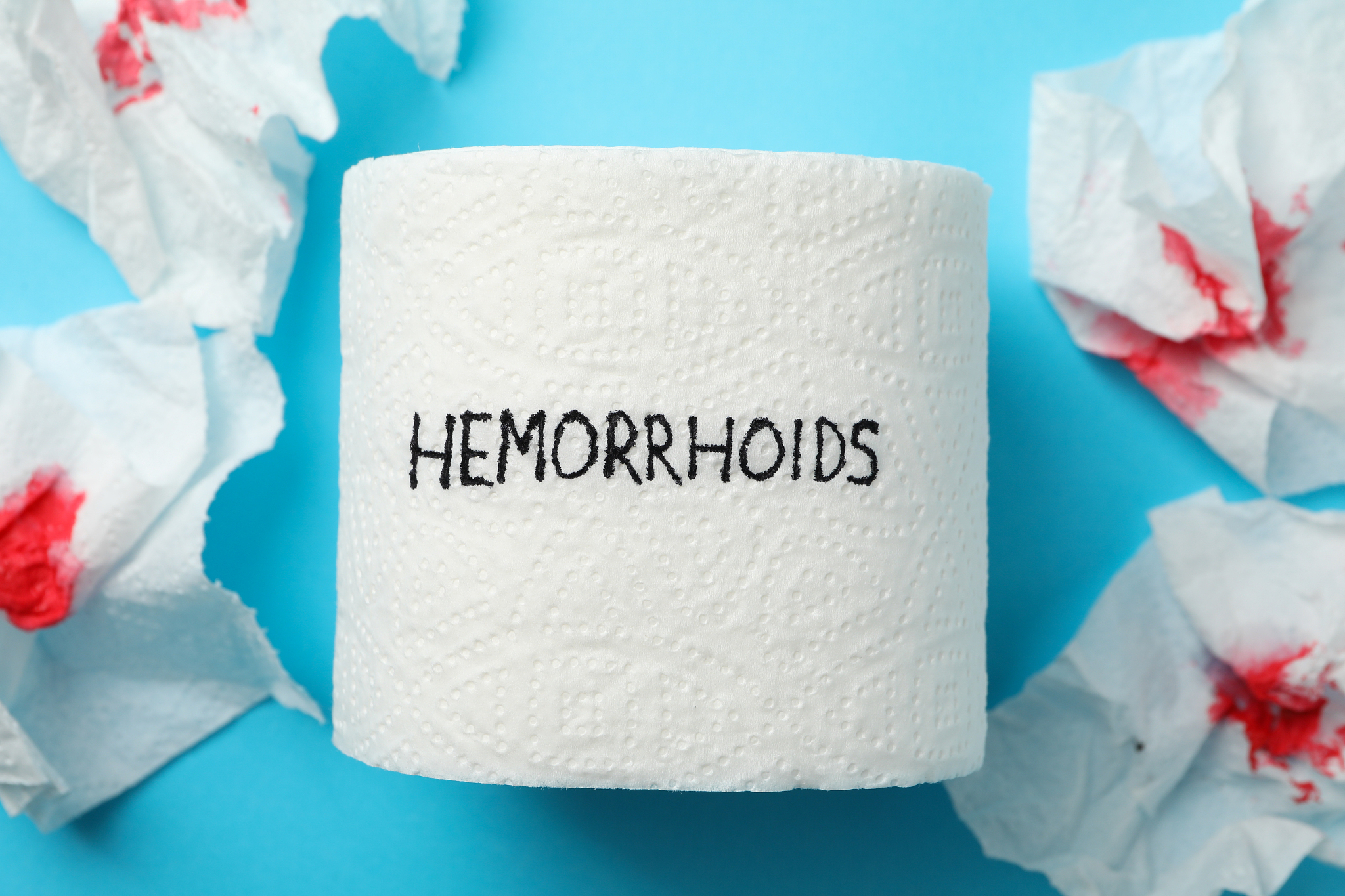 toilet paper with hemorrhoids and paper with blood on blue backg