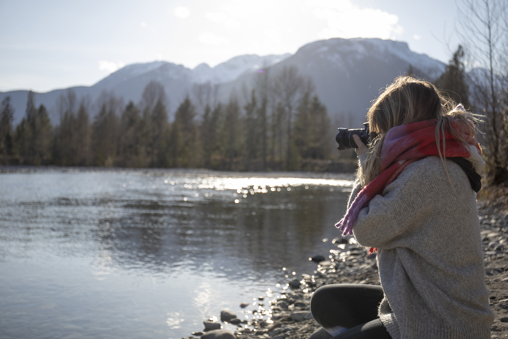 young woman takes picture with dslr camera, on mountain riverban