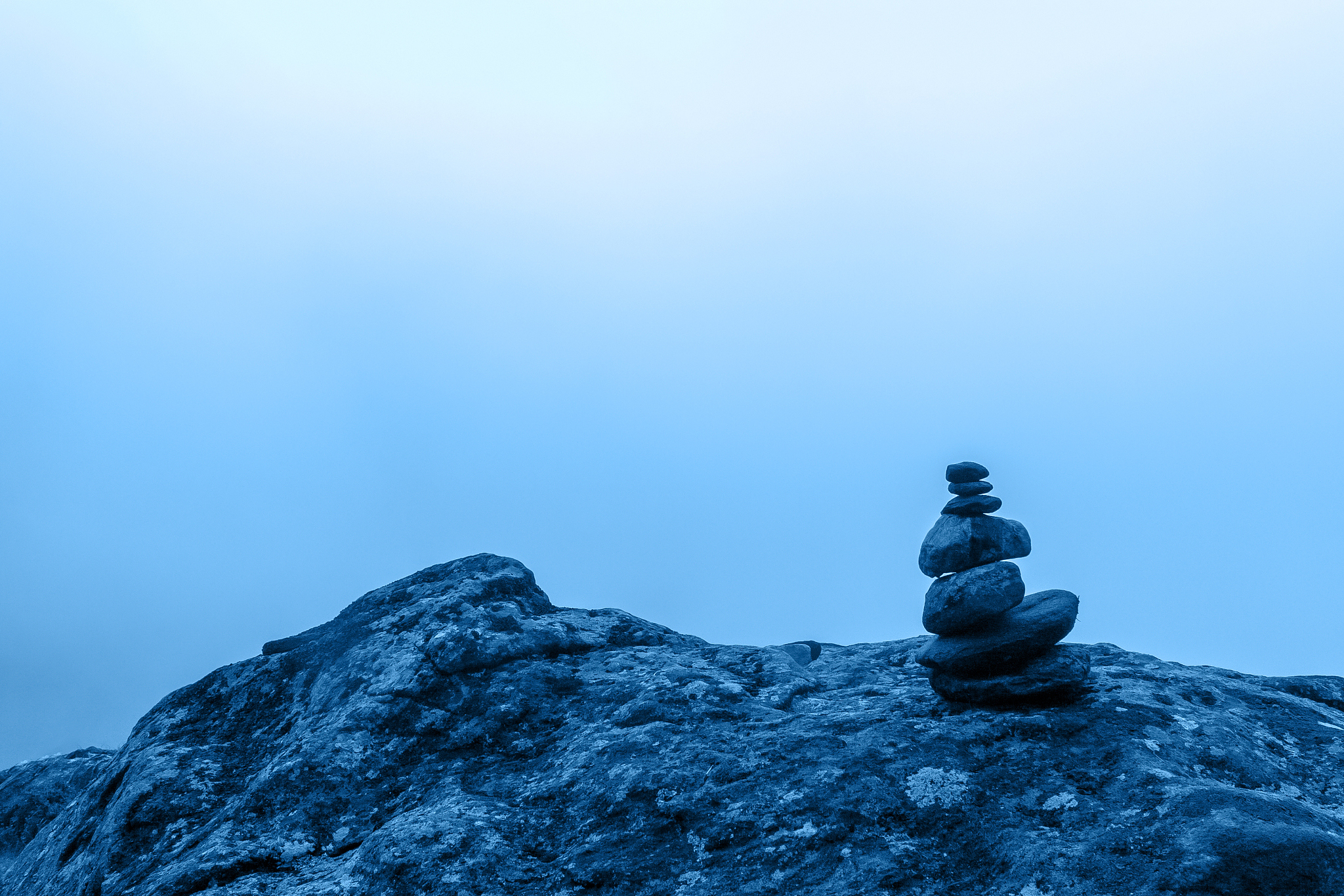minimalism. a small cairn stands on a large boulder with dense f
