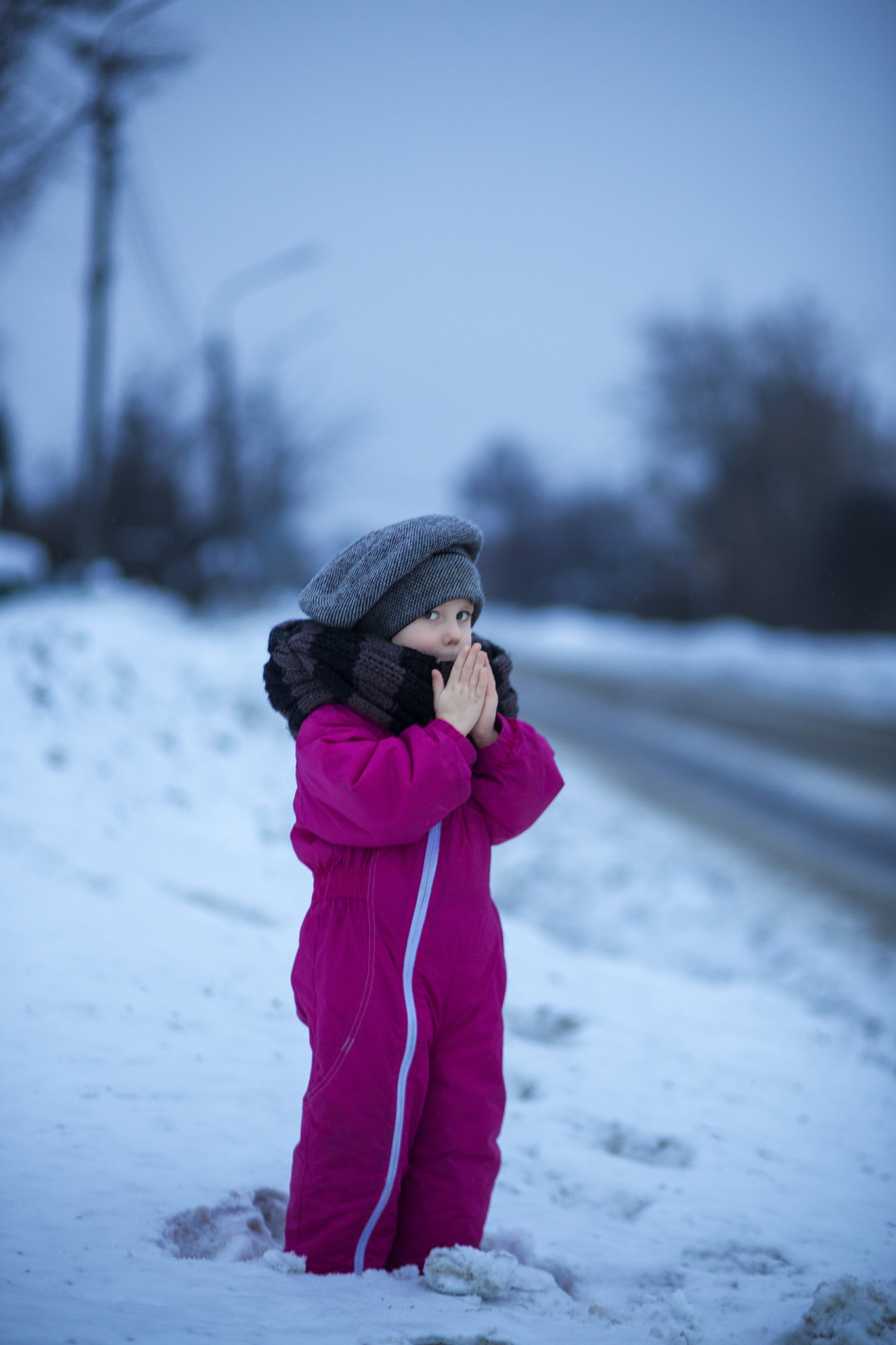 little girl warms her hands with her breath on a winter evening 