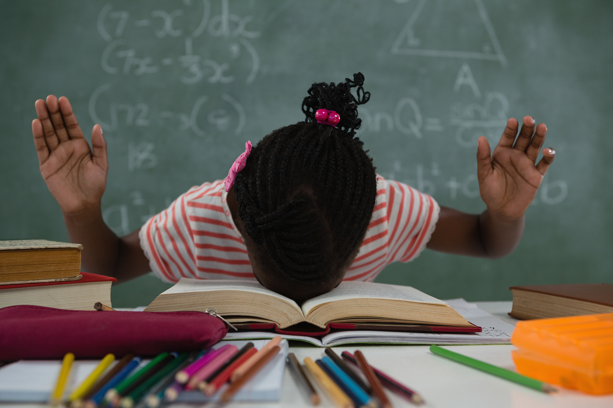 schoolgirl lying on an open books in classroom