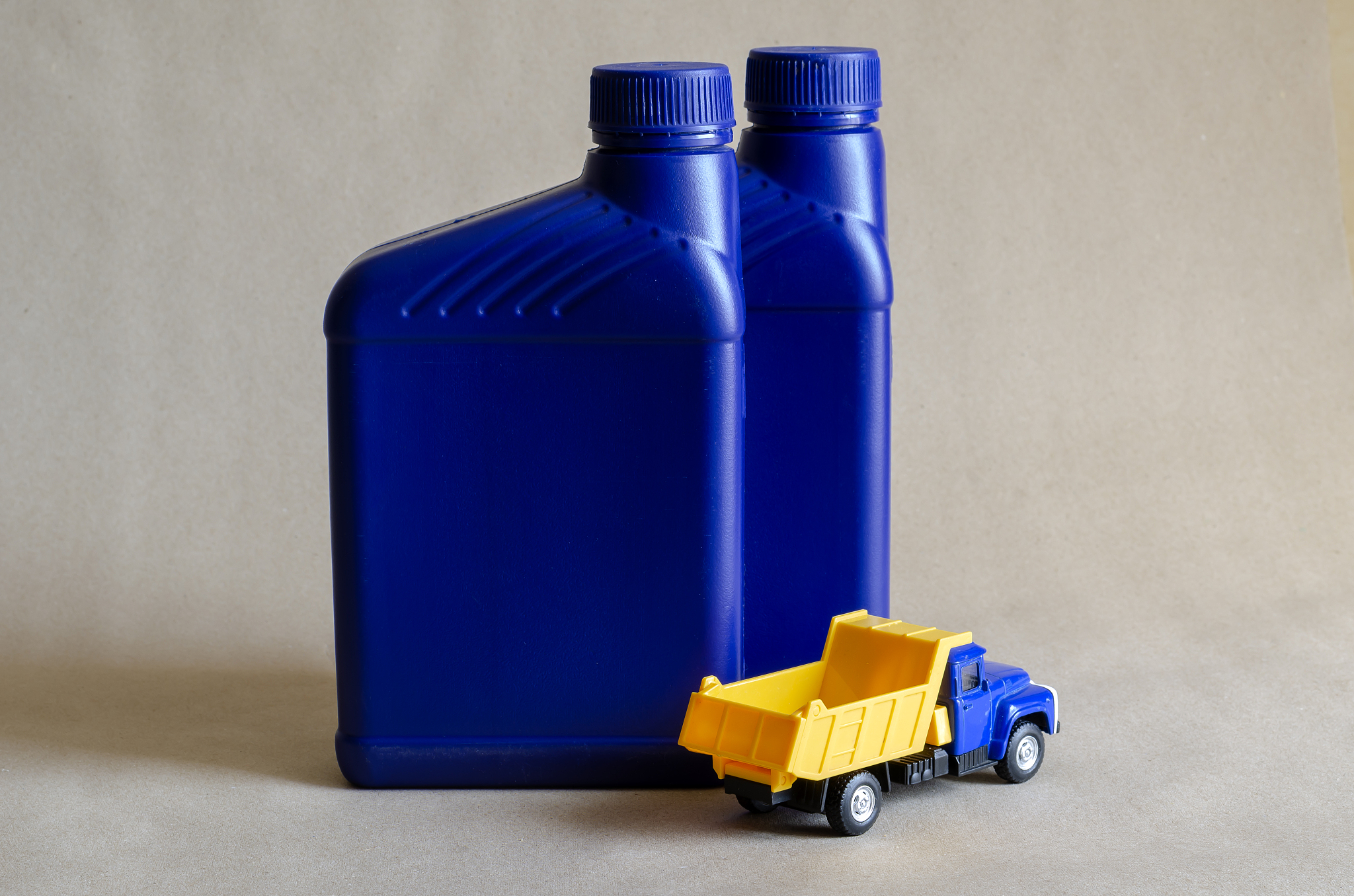 two plastic canisters with car oils and a toy dump truck.