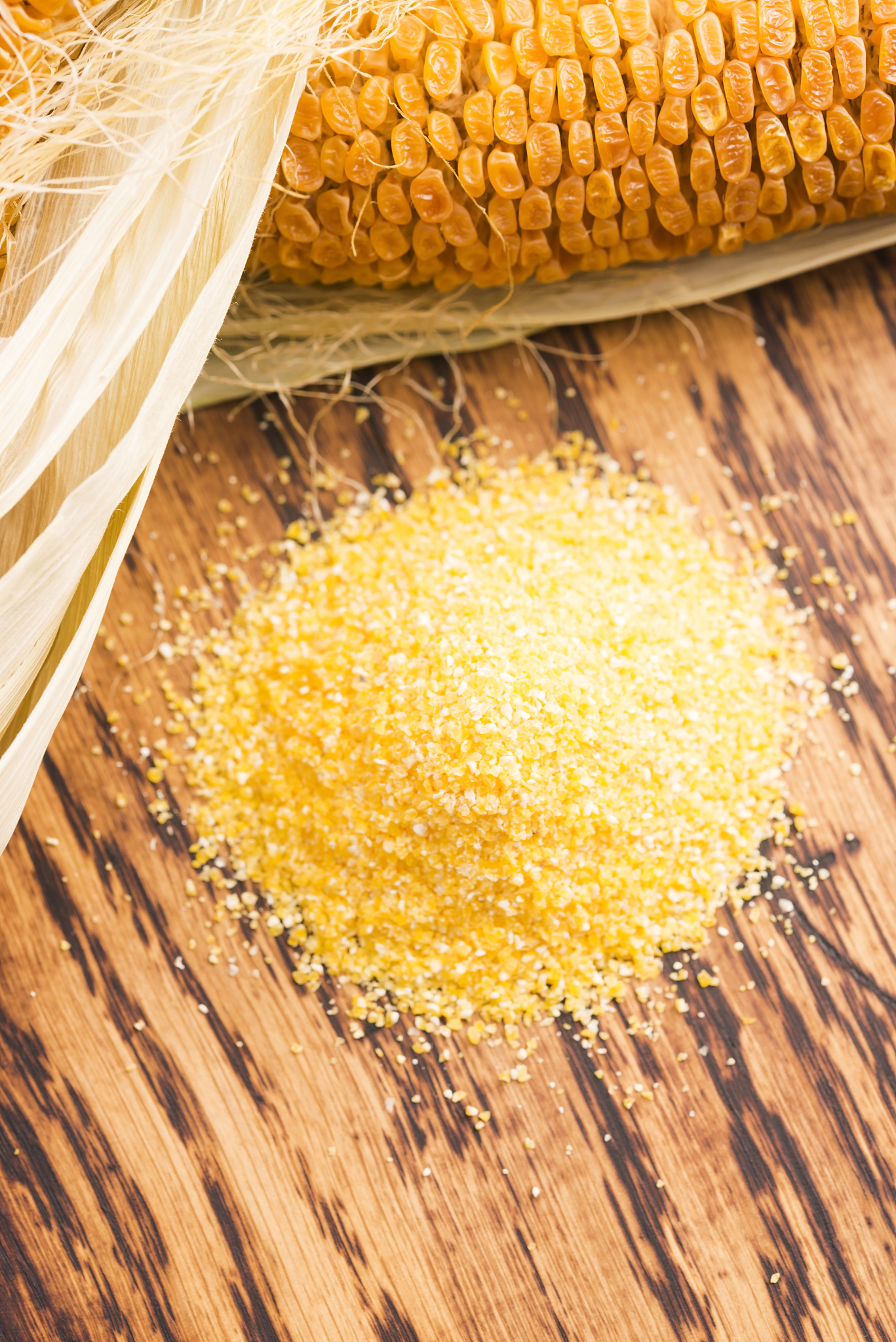 corn groats and seeds, corncobs on wooden rustic table