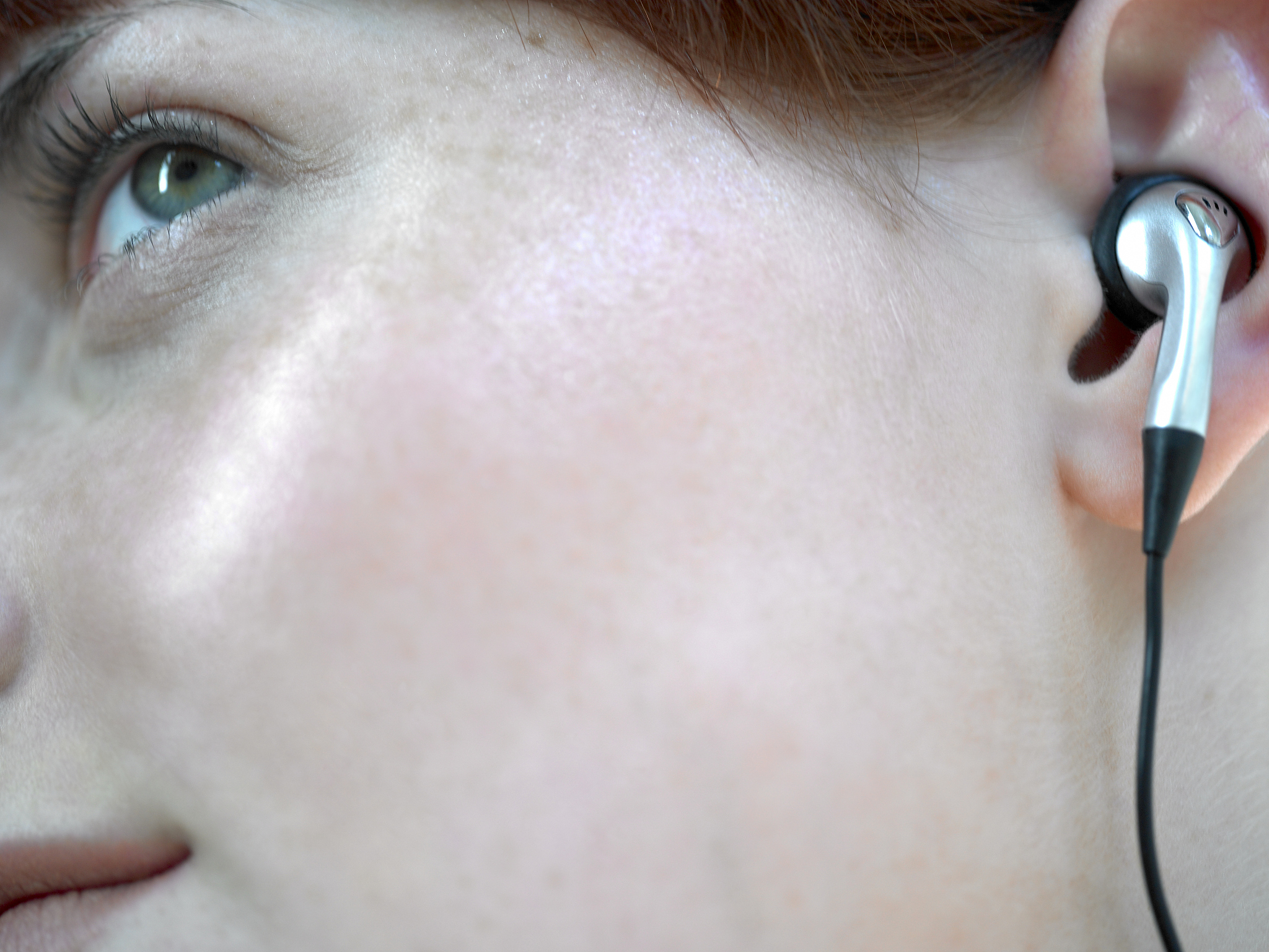 young woman using earphones, close-up of face