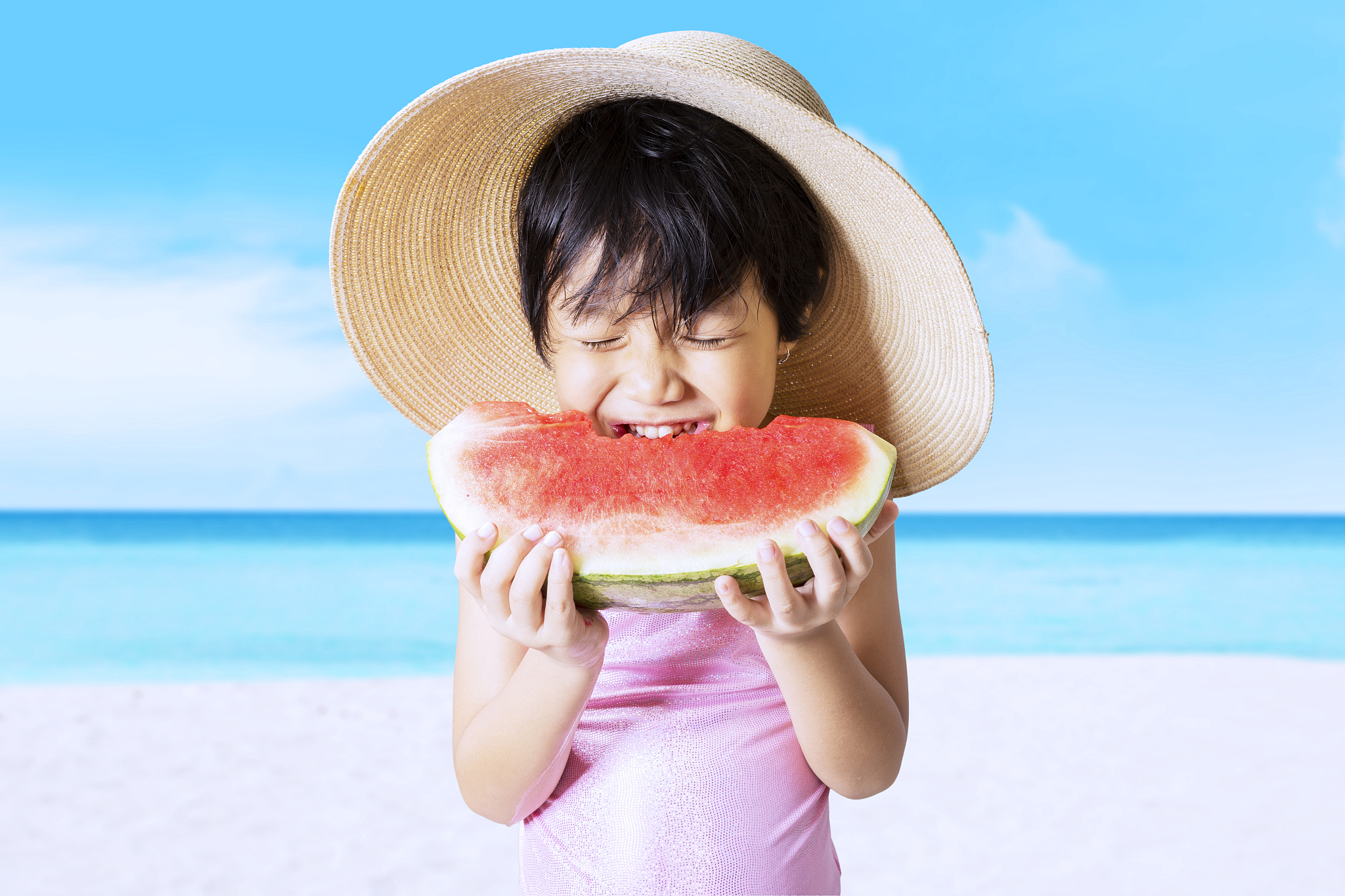 child eats watermelon on the seaside