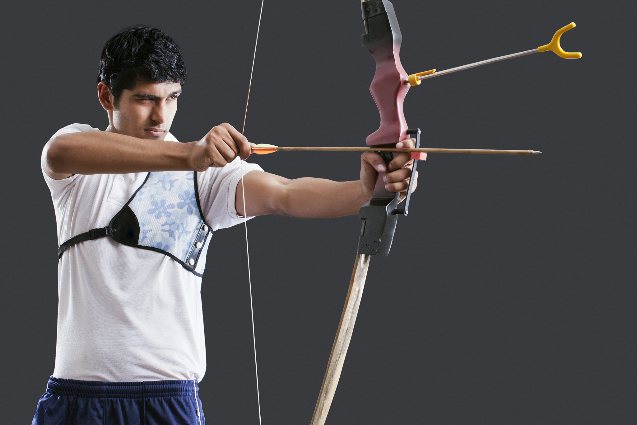 an indian male archer aiming over black background