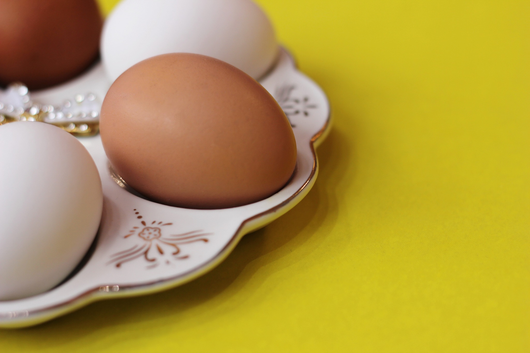 white and brown eggs lie on a special plate on a yellow backgrou