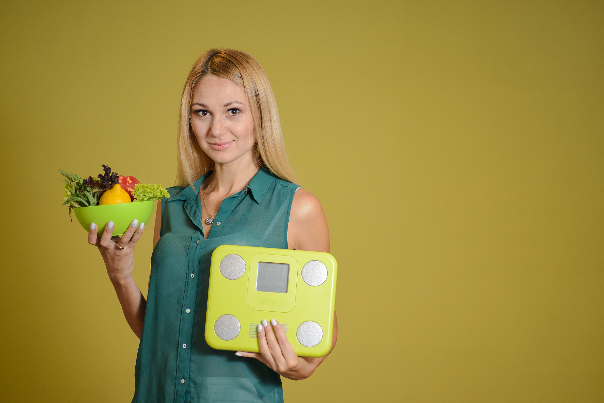portrait of a young beautiful woman with vegetables and weights 